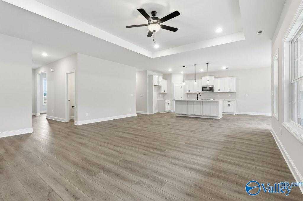 Open-concept kitchen with white island cabinets, pendant lights, dual ceiling fans, and hardwood floors in Davidson Homes The Rockford B, Hartselle, AL