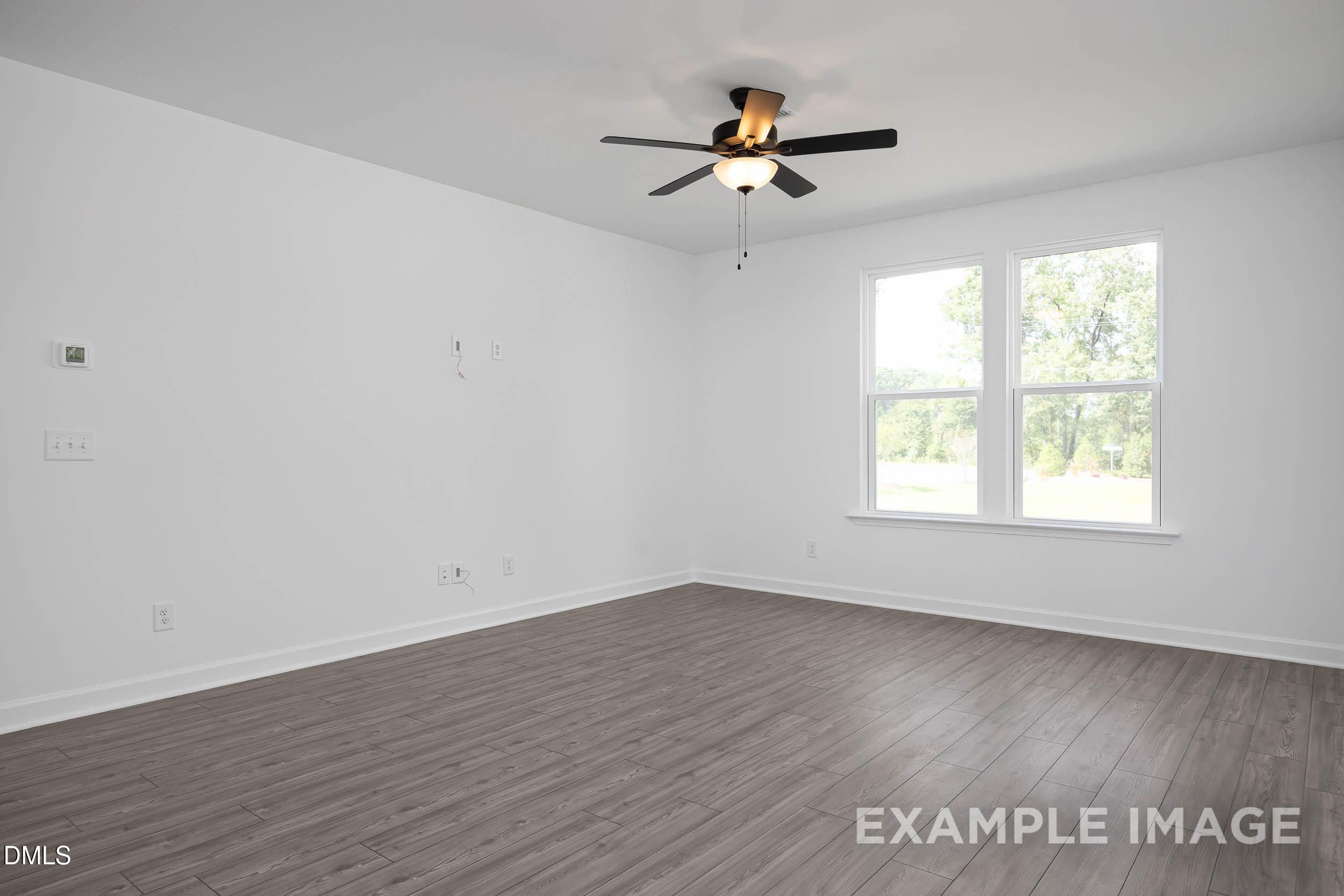 Bright empty bedroom with light hardwood floors, white walls, large windows, and ceiling fan in The Willow D, Zebulon, NC