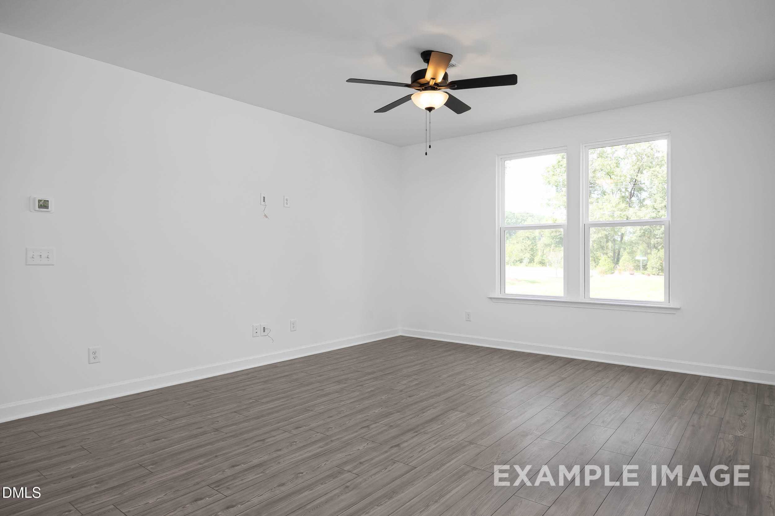 Bright empty bedroom with light hardwood floors, white walls, large windows, and ceiling fan in The Willow D, Zebulon, NC