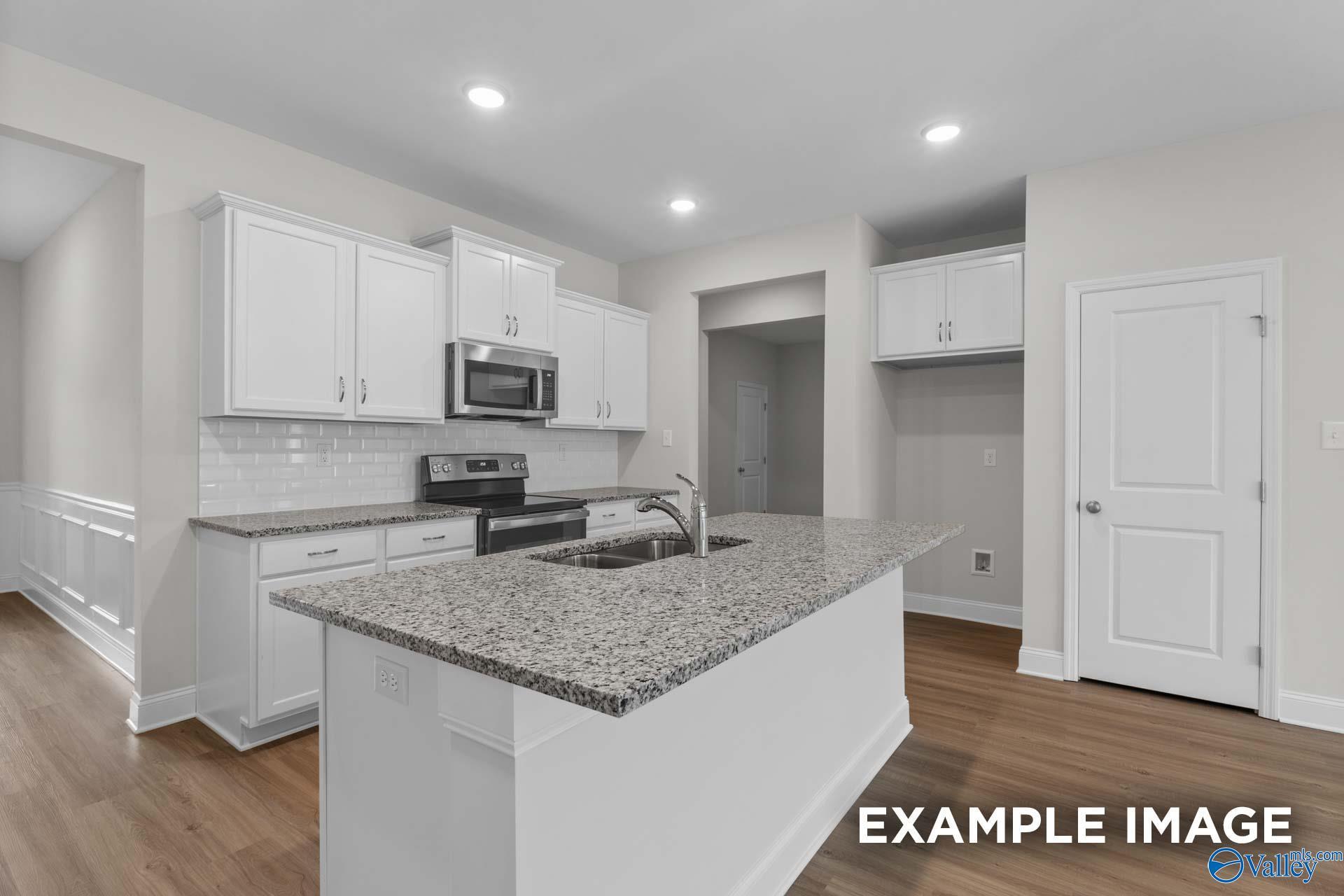 Modern kitchen with white cabinets, granite island sink, subway tile backsplash, stainless appliances in Davidson Homes The Cumberland D, Decatur AL