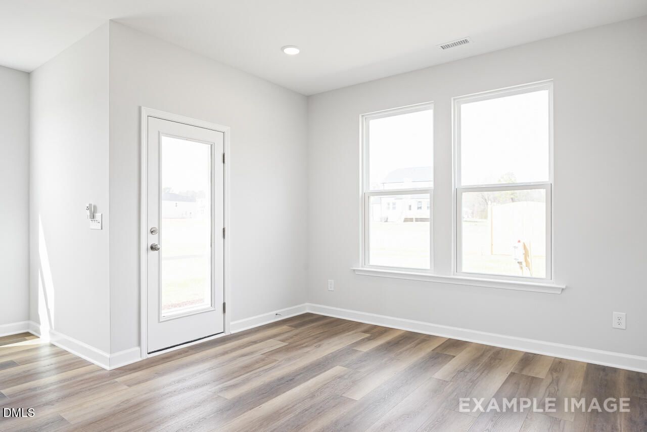 Empty bedroom with luxury vinyl plank flooring, white walls, large windows in Davidson Homes The Daphne C, Zebulon NC