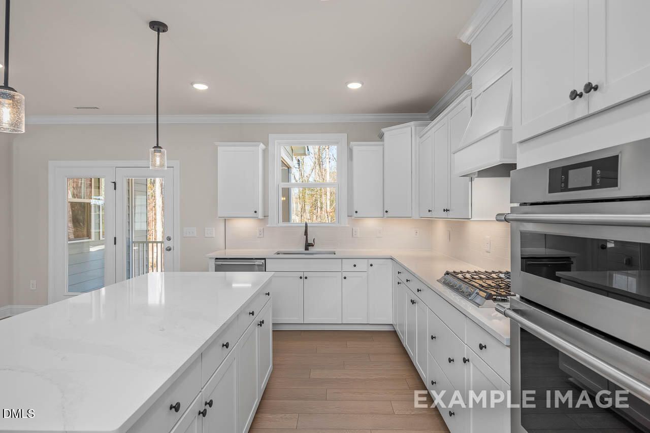 Modern white kitchen with quartz island, stainless appliances, French doors to deck in The Crawford D by Davidson Homes, Angier, NC
