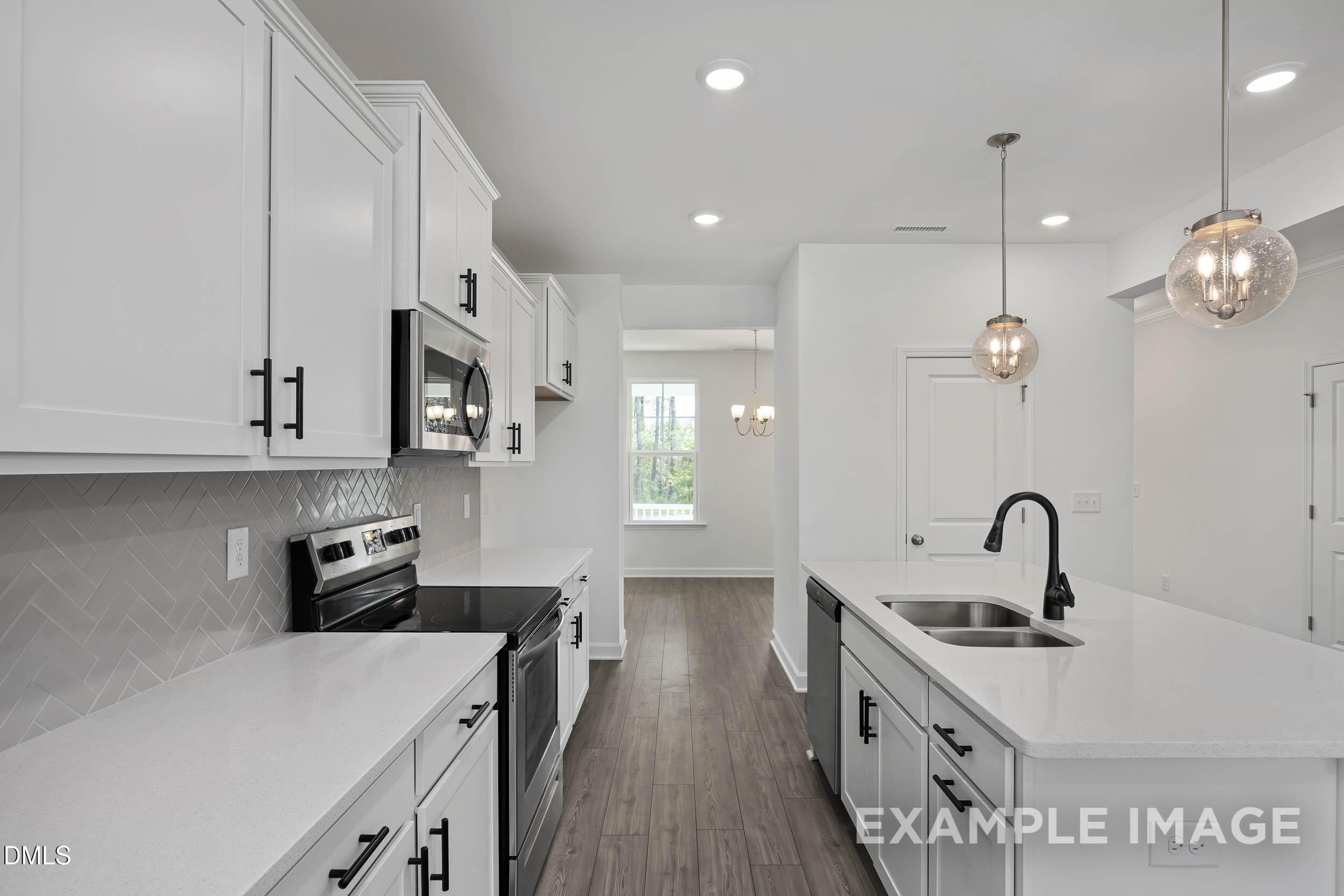 Modern white kitchen with subway tile backsplash, stainless appliances, and quartz counters in Davidson Homes The Willow D, Zebulon, NC