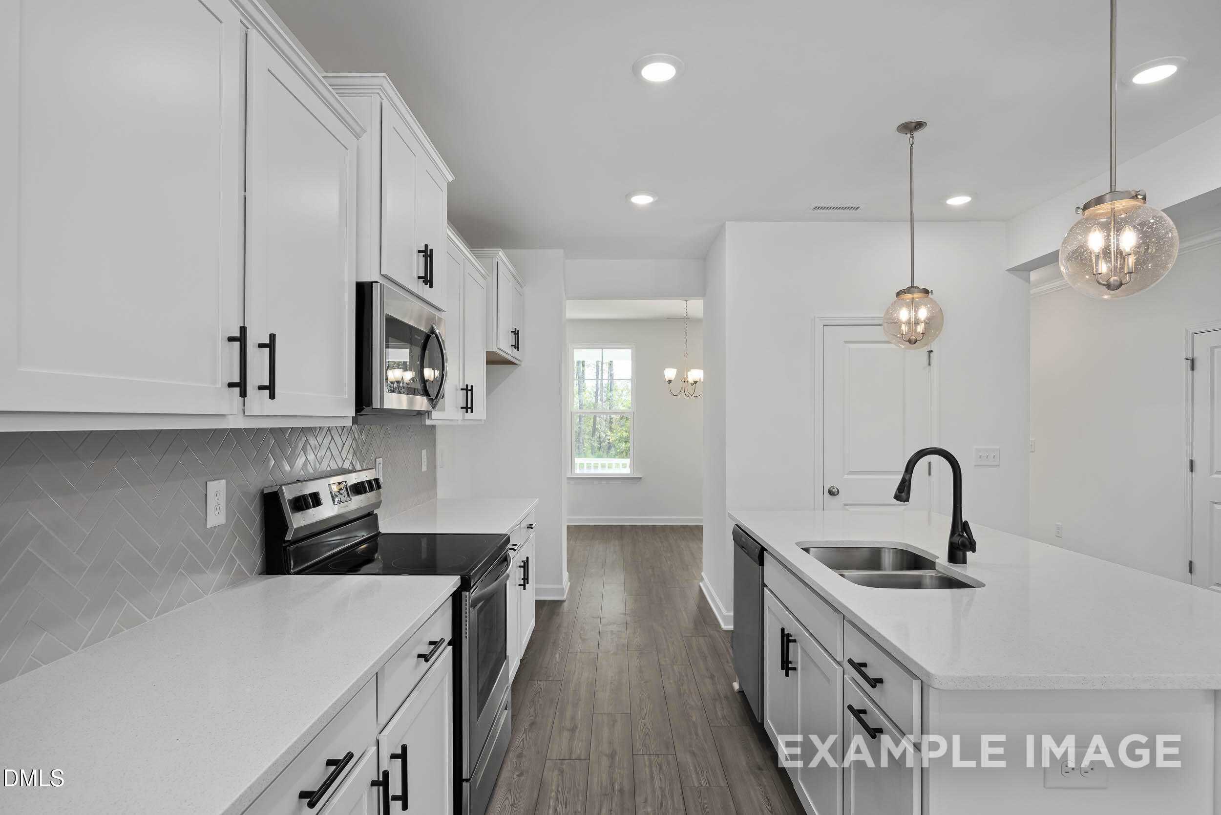 Modern white kitchen with subway tile backsplash, stainless appliances, and quartz counters in Davidson Homes The Willow D, Zebulon, NC