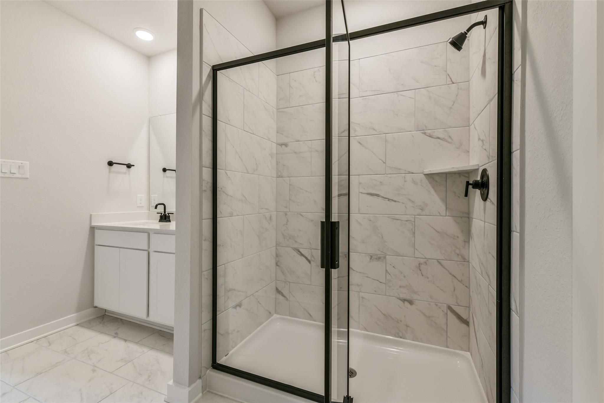 Elegant master bathroom with frameless glass shower, white subway tile, and single vanity in Davidson Homes The Daphne H, Crosby Texas