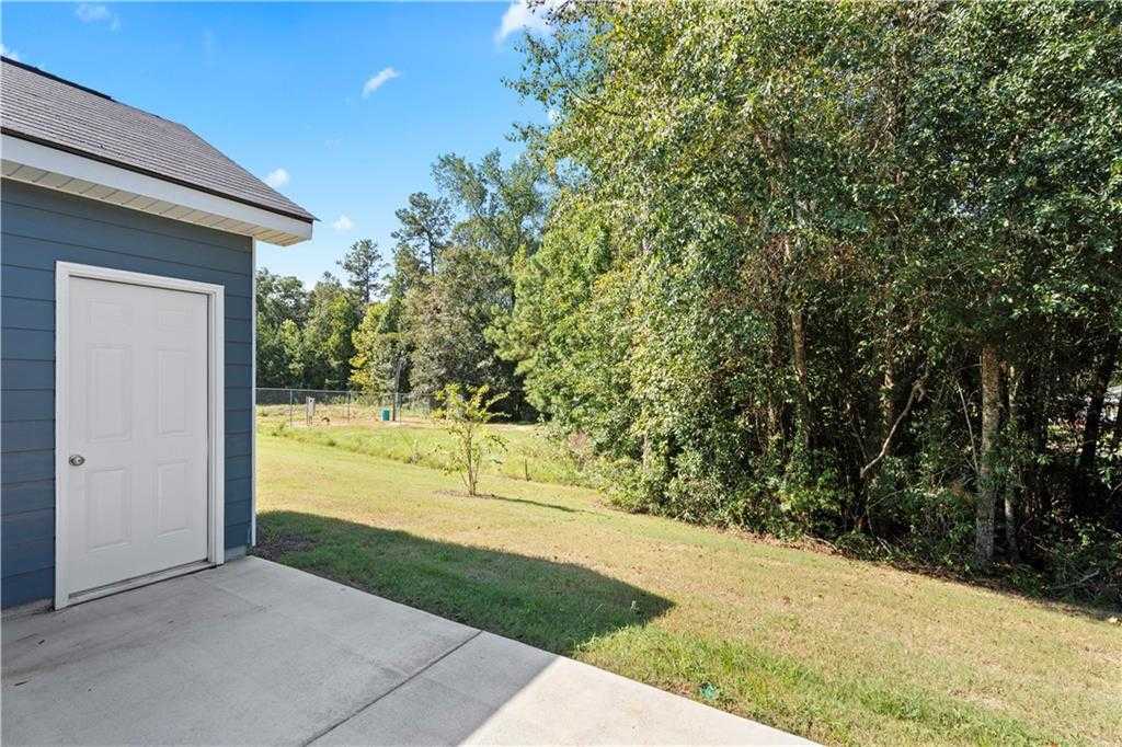 1-car garage with blue door on Davidson Homes The Washington, concrete pad, grassy yard, wooded backdrop in Summer Vineyard, Phenix City, Alabama