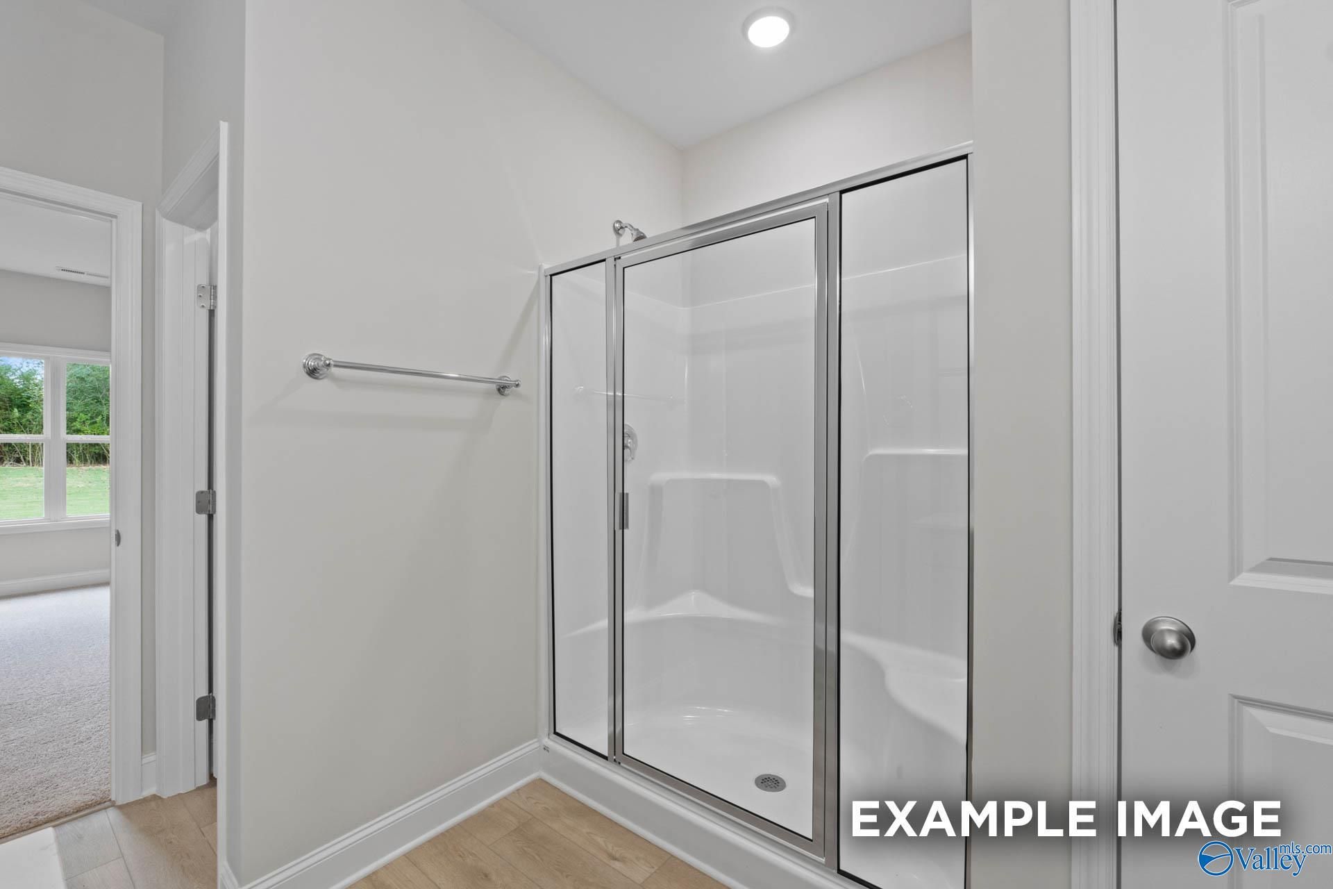 Modern glass shower enclosure with white tile and chrome fixtures in master bathroom, Davidson Homes The Franklin C, Toney, Alabama