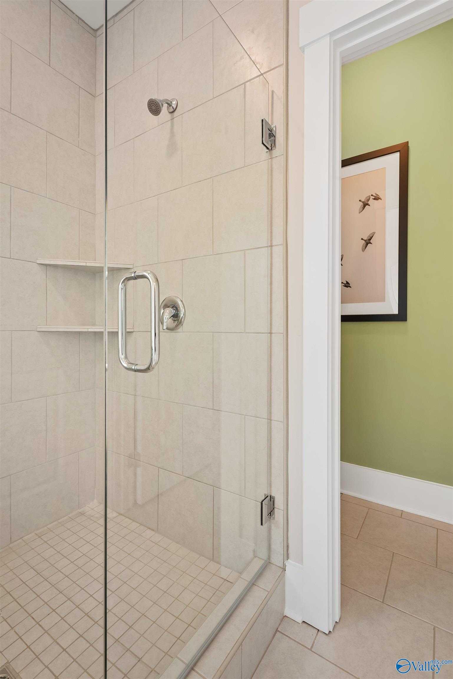 Modern frameless glass shower with subway tile walls and chrome fixtures in master bath of Davidson Homes The Daphne, Harvest, Alabama