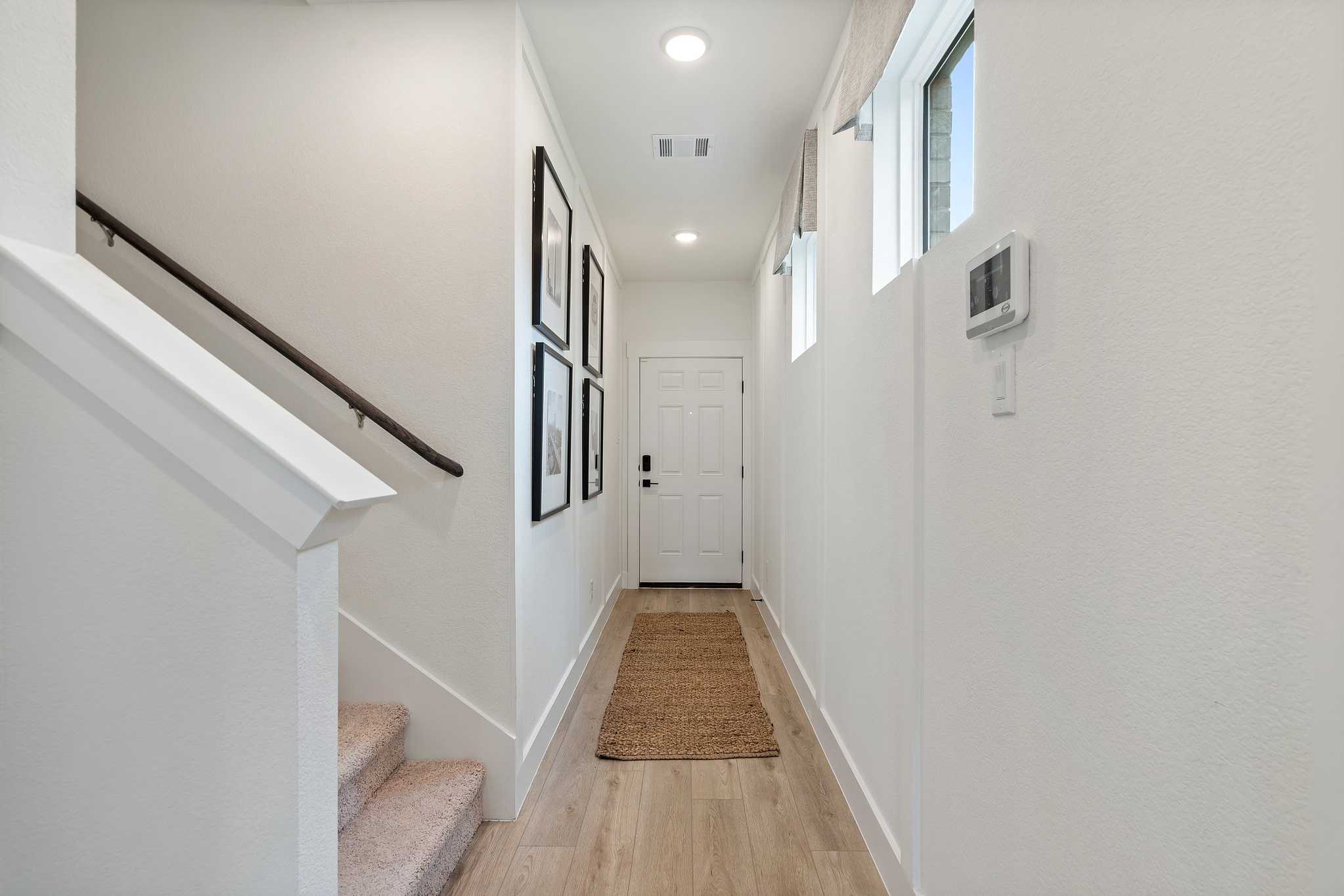 Spacious entry hallway in The Wake D 2-story home with white shiplap walls, oak stairs, hardwood floors, and framed art
