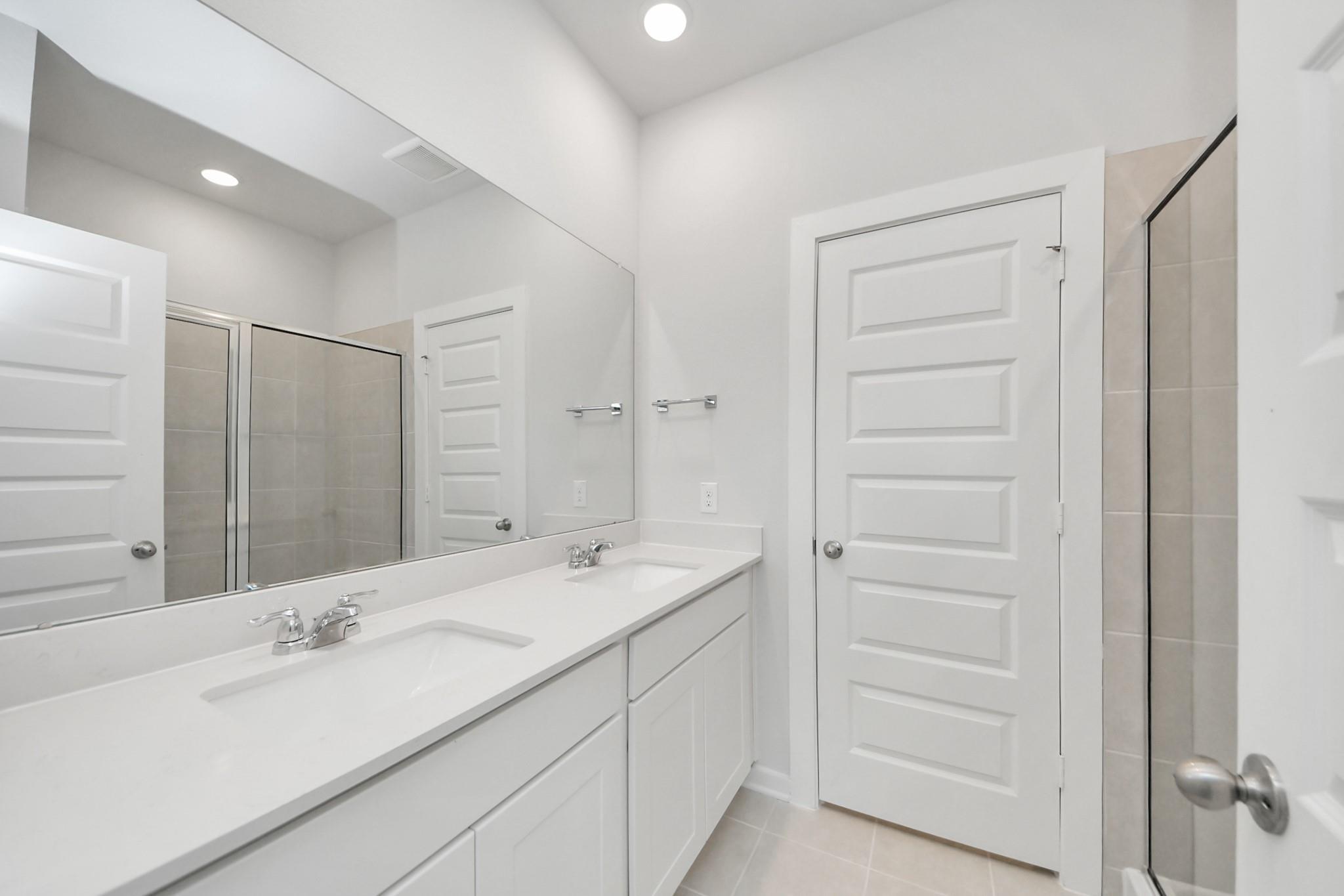 Modern bathroom with double vanity and walk-in shower in The Frio F floor plan at Liberty Estates, Cleveland, Texas.