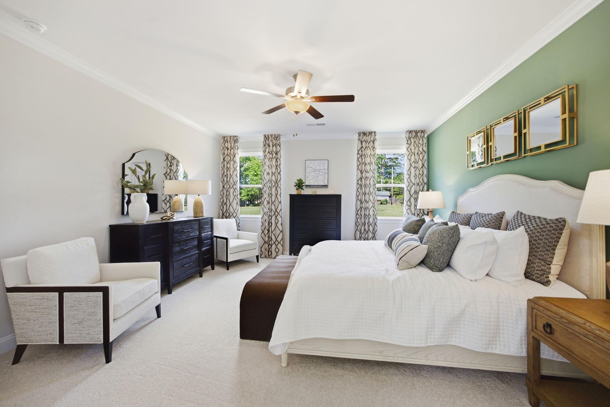 Spacious master bedroom at Enclave at Belmont in Belmont NC with king bed, ceiling fan, green accent wall, and sheer-curtained windows