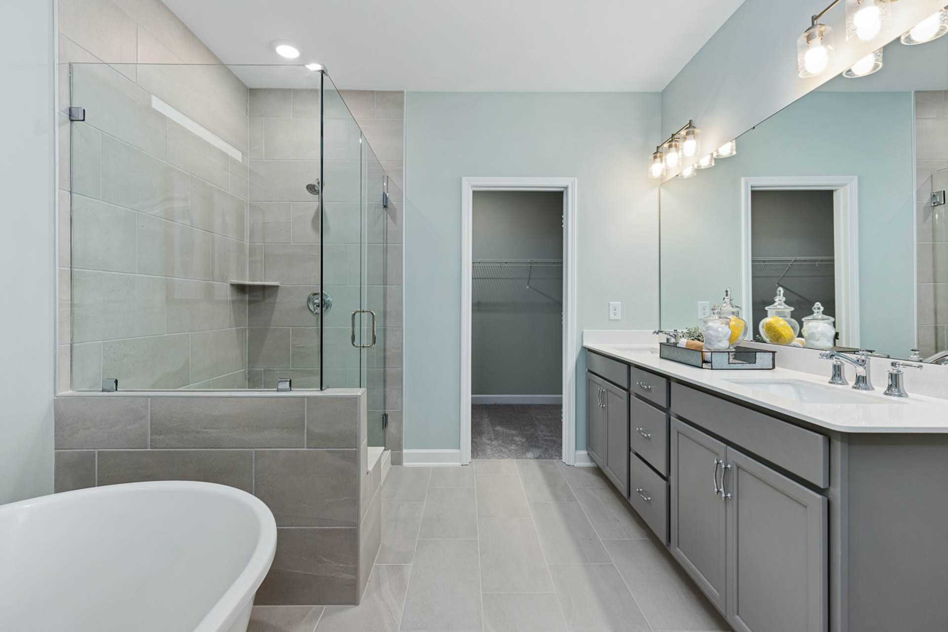Spacious master bath at Weatherford East in Angier NC with glass shower, freestanding tub, double vanity, and soft blue walls