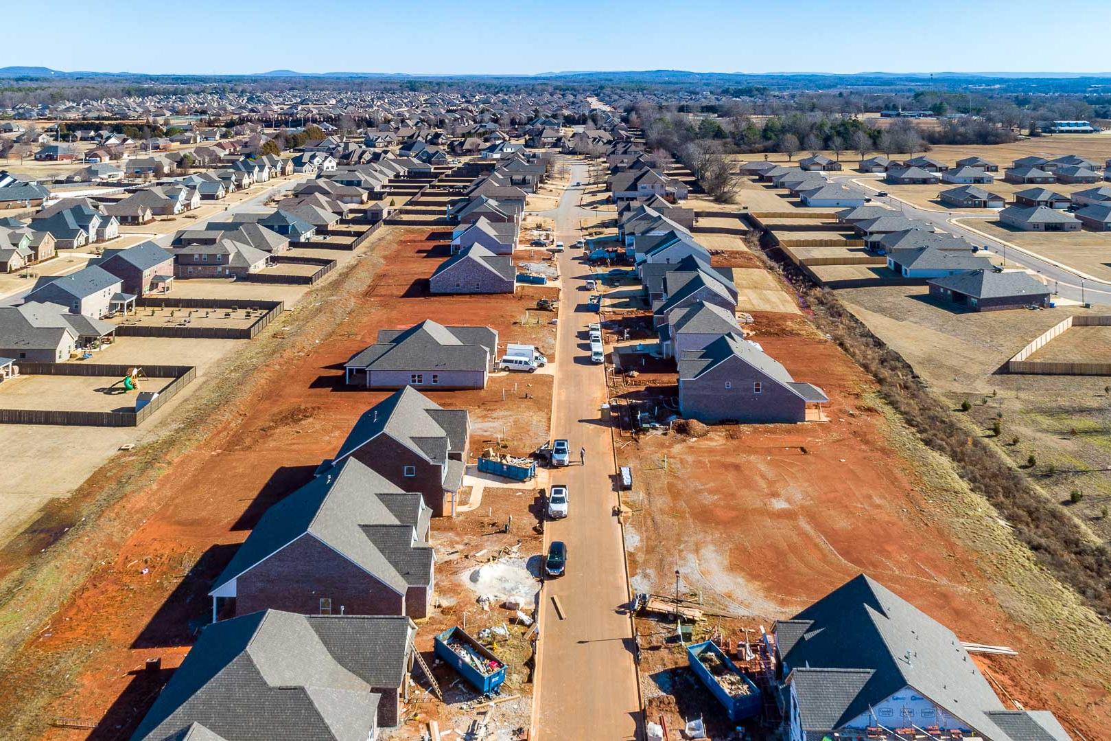 Aerial view of new homes under construction in Old Stone Athens Alabama by Davidson Homes with red dirt roads and building sites