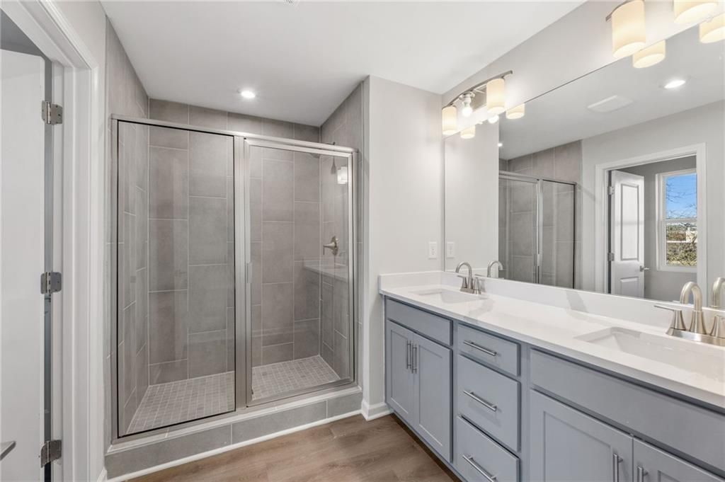 Elegant master bathroom with double gray vanity, white quartz counters, and glass tile shower in Davidson Homes The Marion A, Winder, GA