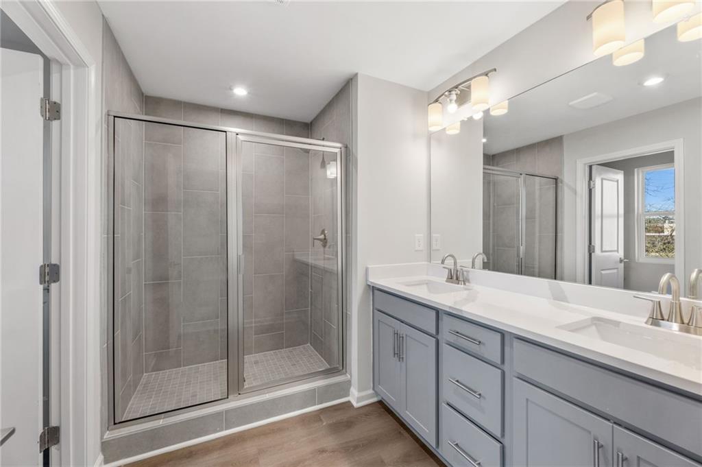 Elegant master bathroom with double gray vanity, white quartz counters, and glass tile shower in Davidson Homes The Marion A, Winder, GA