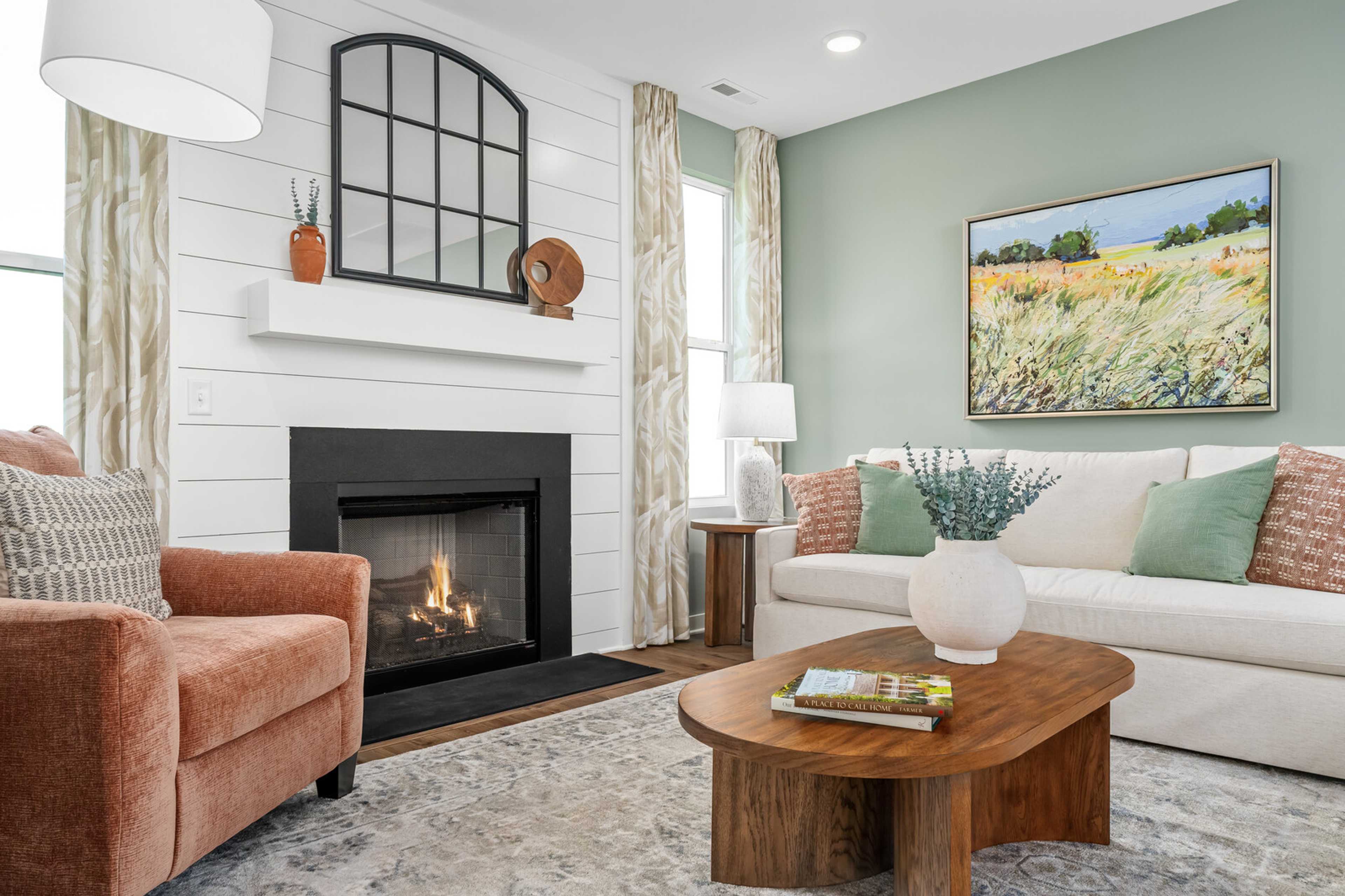 Cozy living room in Calista Farms White House TN with black gas fireplace, shiplap walls, orange armchair, and neutral decor