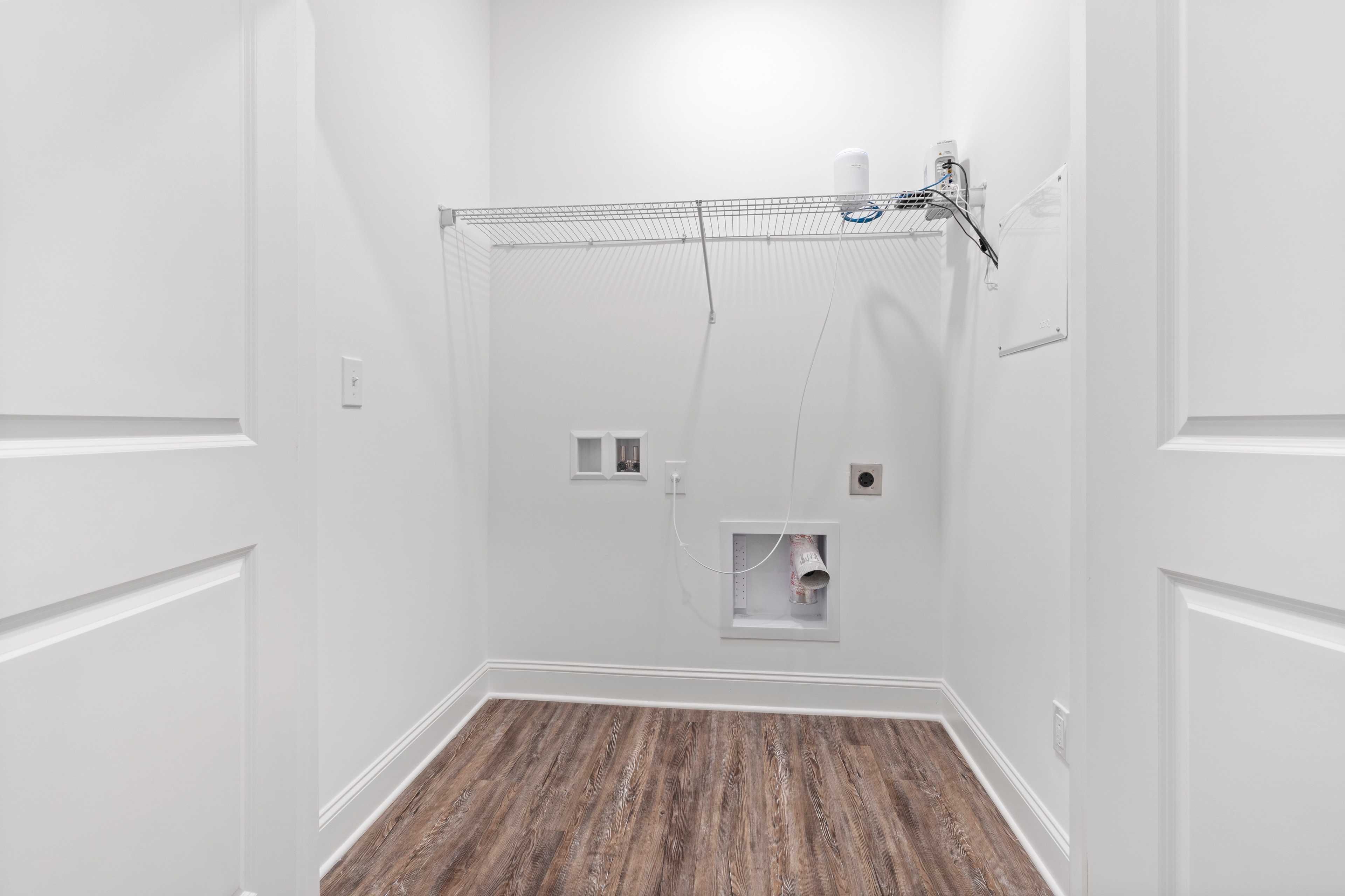 Spacious walk-in laundry room at The Retreat at Hollon Meadow in Decatur AL with wire shelving, washer dryer hookups, and hardwood floors