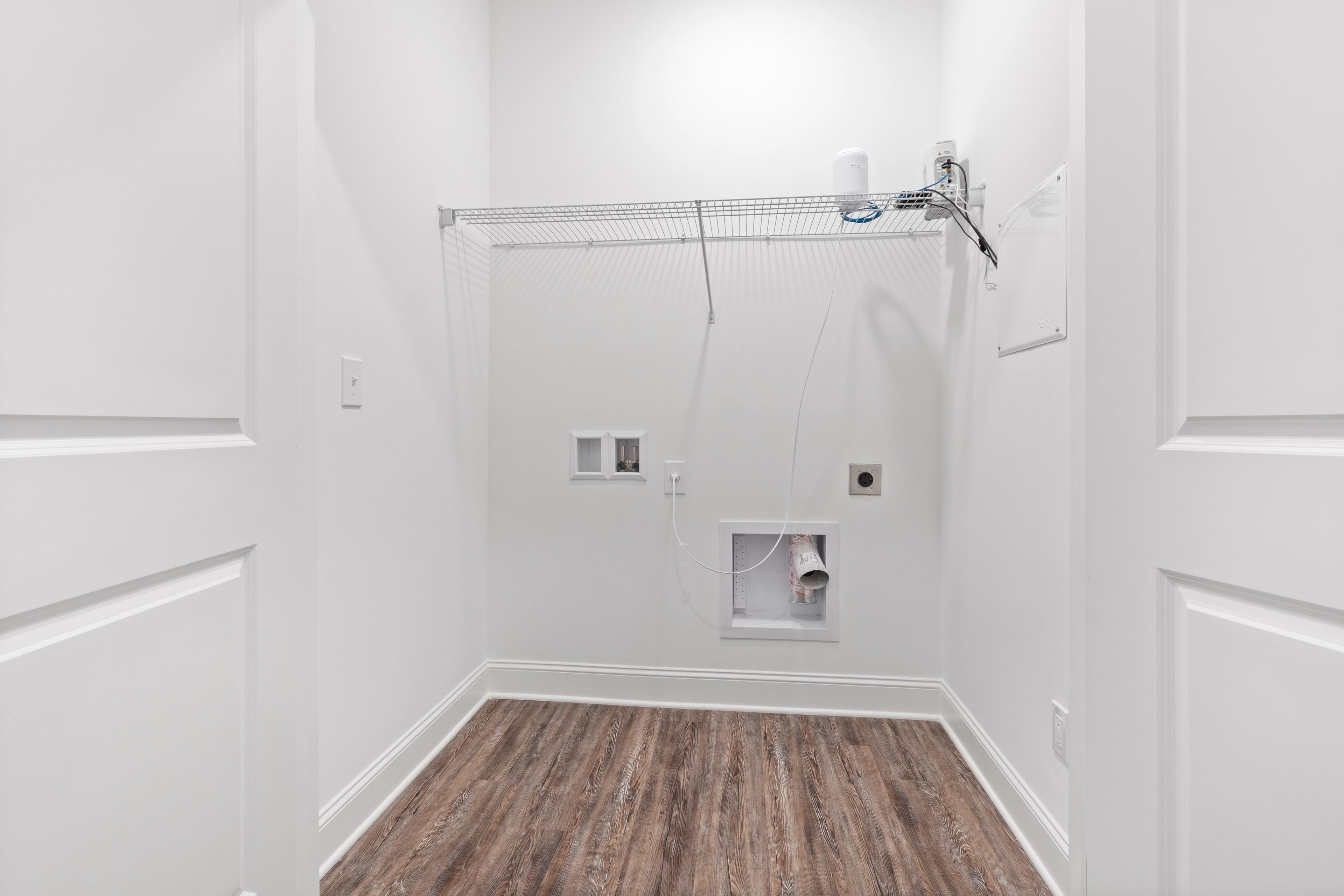 Spacious laundry closet in The Cumberland home with wire shelving, washer-dryer hookups, and wood-look flooring