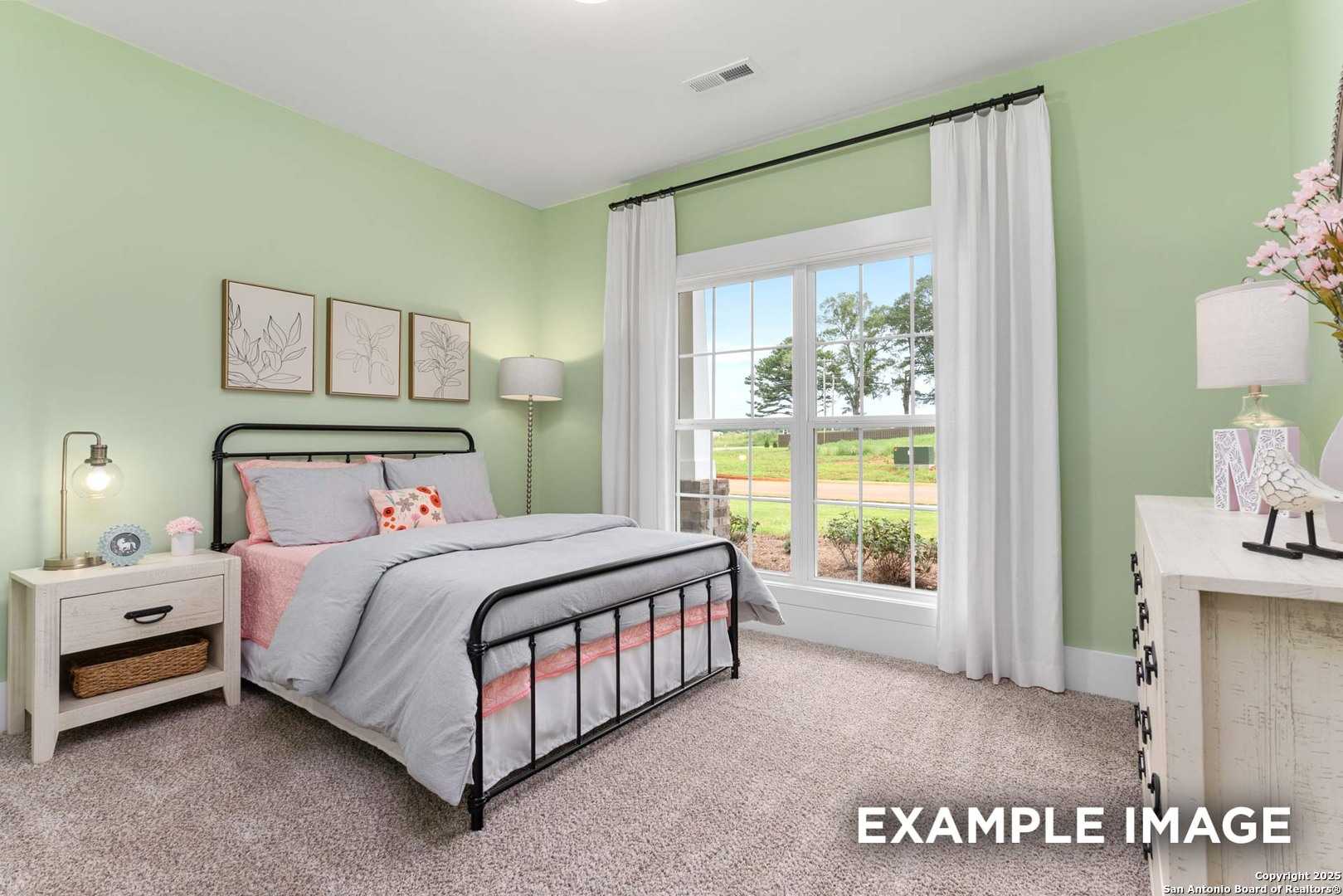 Charming mint green bedroom with wrought iron bed, pink accents, and backyard view in Davidson Homes The Daphne H, Seguin, Texas