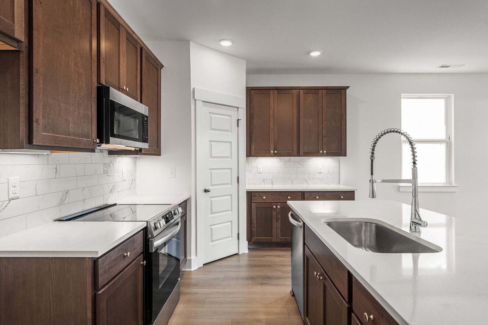 Modern kitchen in The Cottonwood floor plan featuring dark wood cabinets, white quartz countertops, and a large center island.