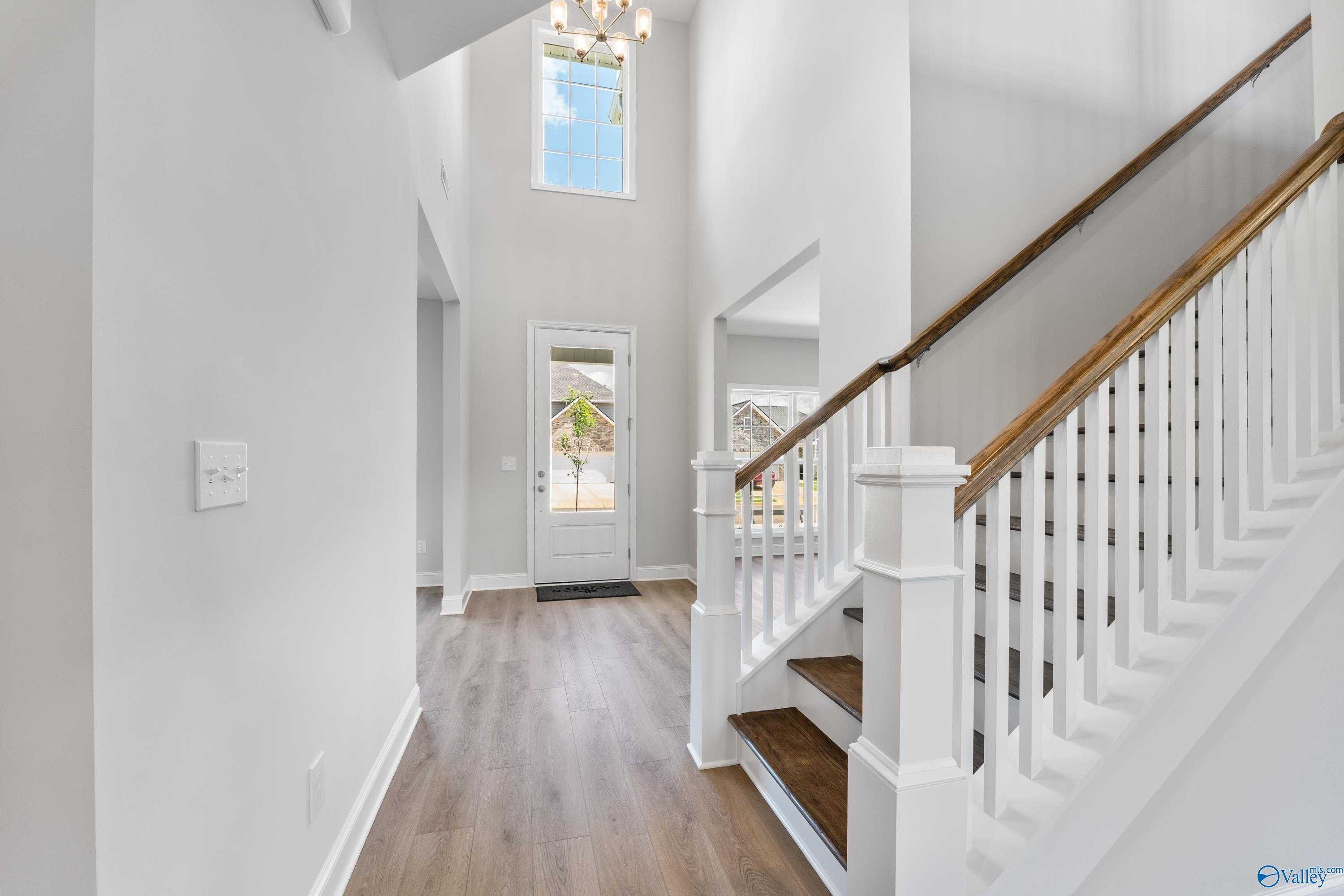 Grand two-story foyer with oak staircase, chandelier, and high ceilings in Davidson Homes The Madison A, Toney, Alabama