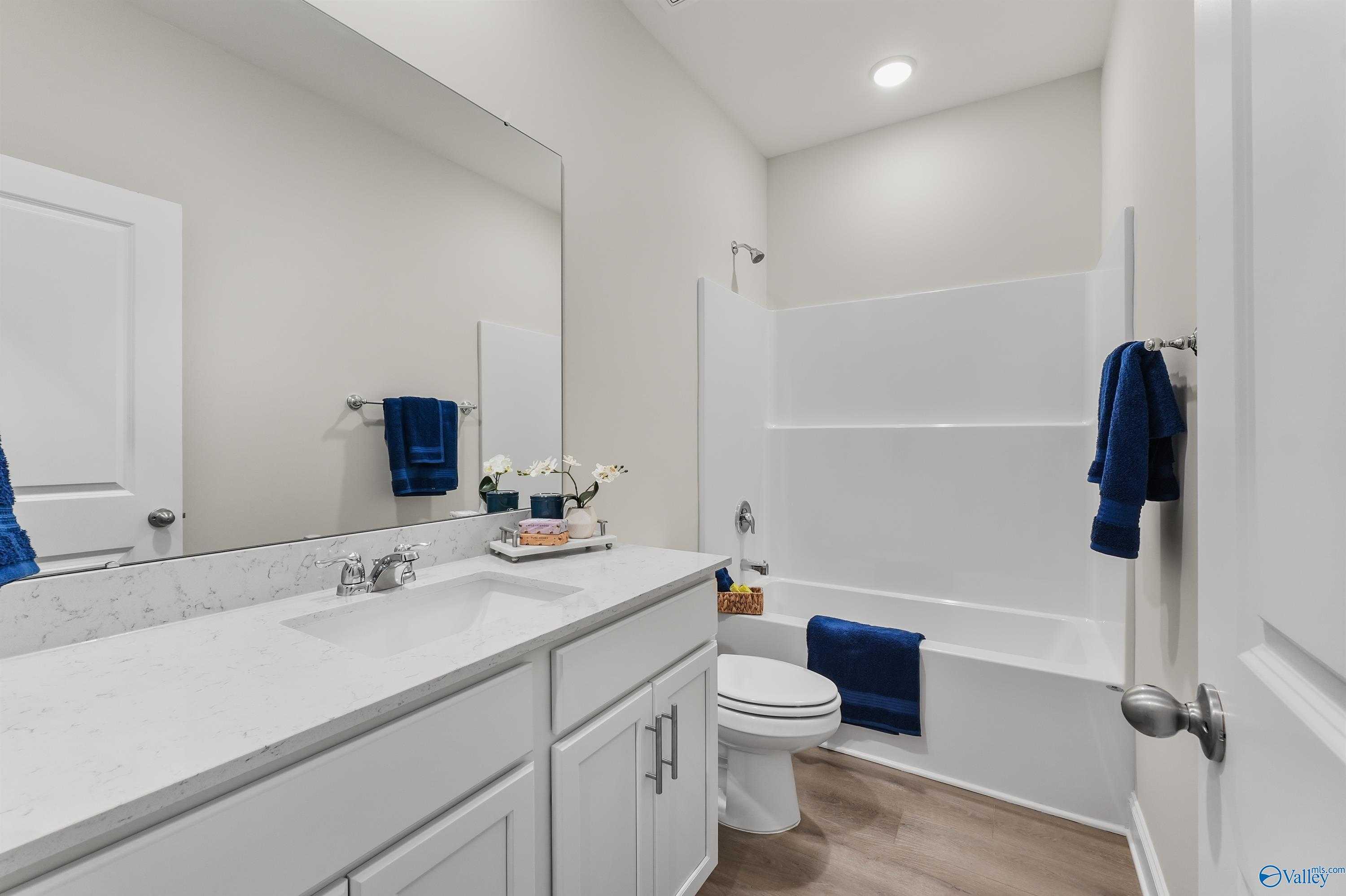 Spacious bathroom featuring white quartz vanity, soaking tub, walk-in shower, and blue accents in Davidson Homes The Asheville C, Huntsville, Alabama