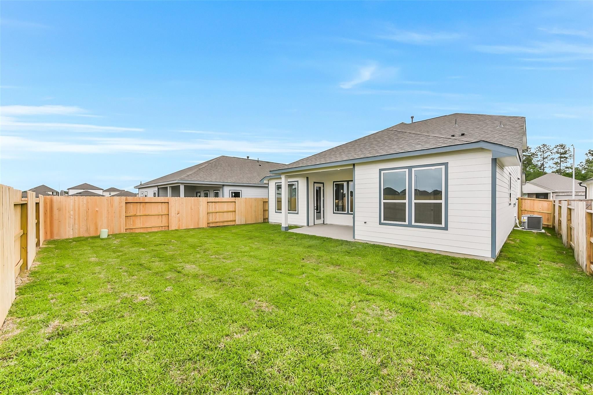 Spacious backyard with covered patio, large windows, and lush green lawn in Davidson Homes Sequoia C, Sundance Cove, Crosby, Texas