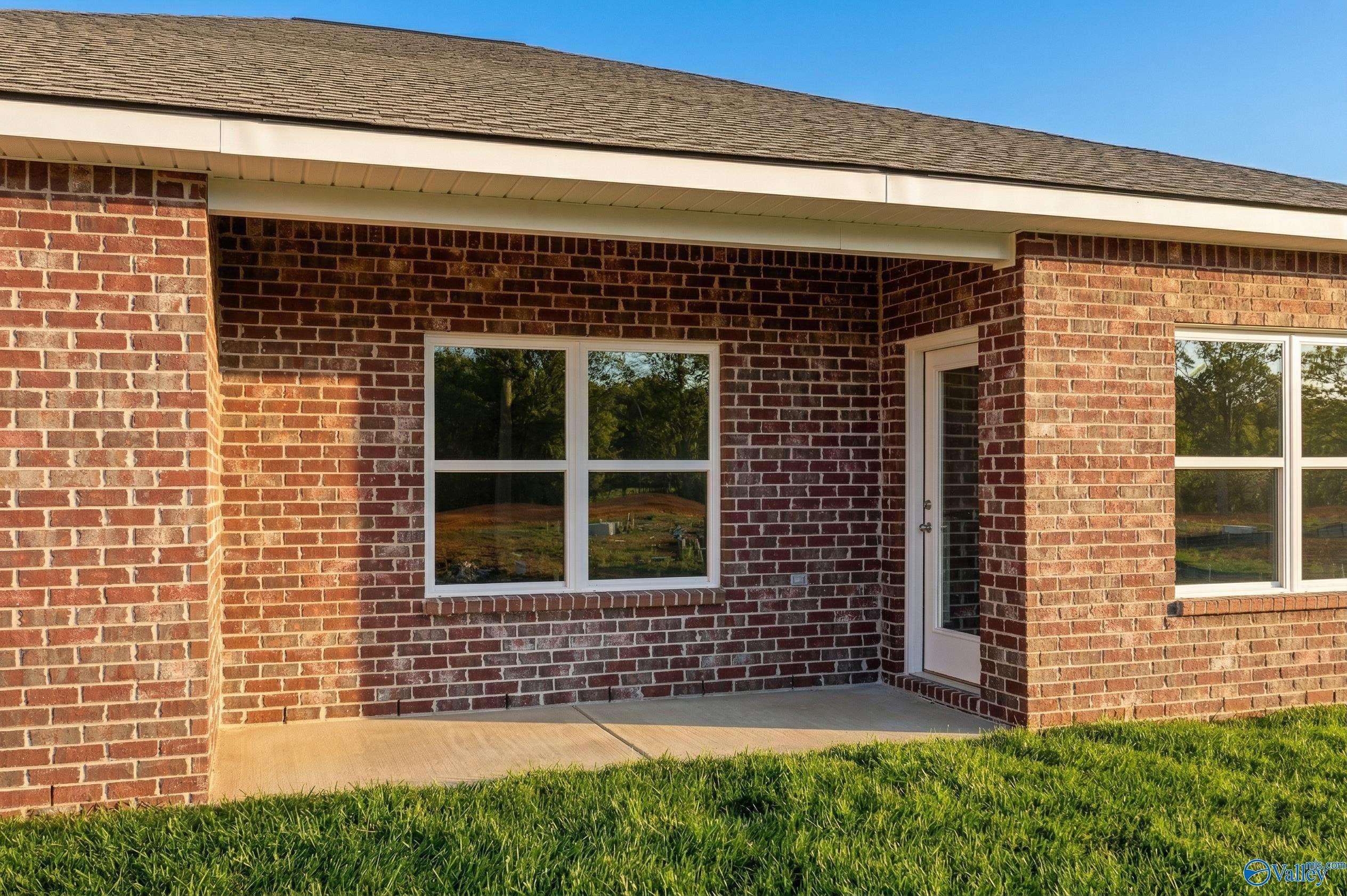 Red brick exterior with concrete patio and backyard view of The Asheville C floor plan in Spragins Cove, Huntsville.