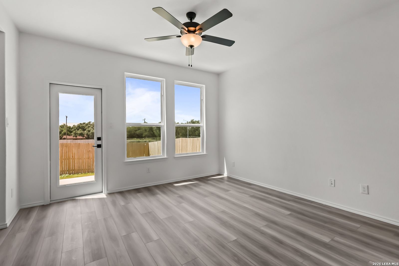 Bright living area with wood-look flooring and backyard access in The Florence B floor plan, Meadows at Oak Creek, TX.