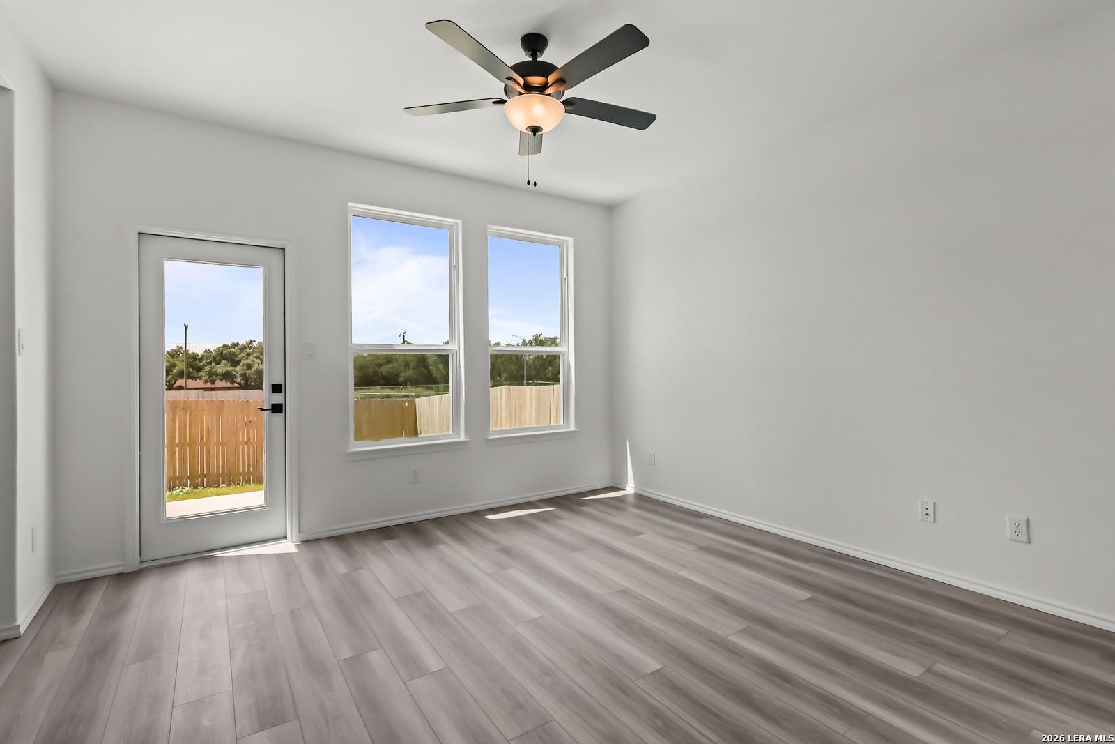 Bright living area with wood-look flooring and backyard access in The Florence B floor plan, Meadows at Oak Creek, TX.