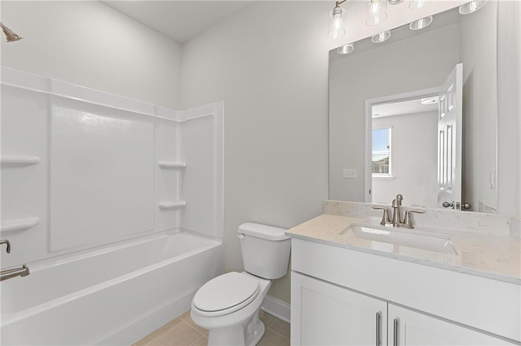 Bright white bathroom with tub-shower combo, toilet, and quartz vanity in Davidson Homes Harrison G plan, Cedar Farms, Winder GA