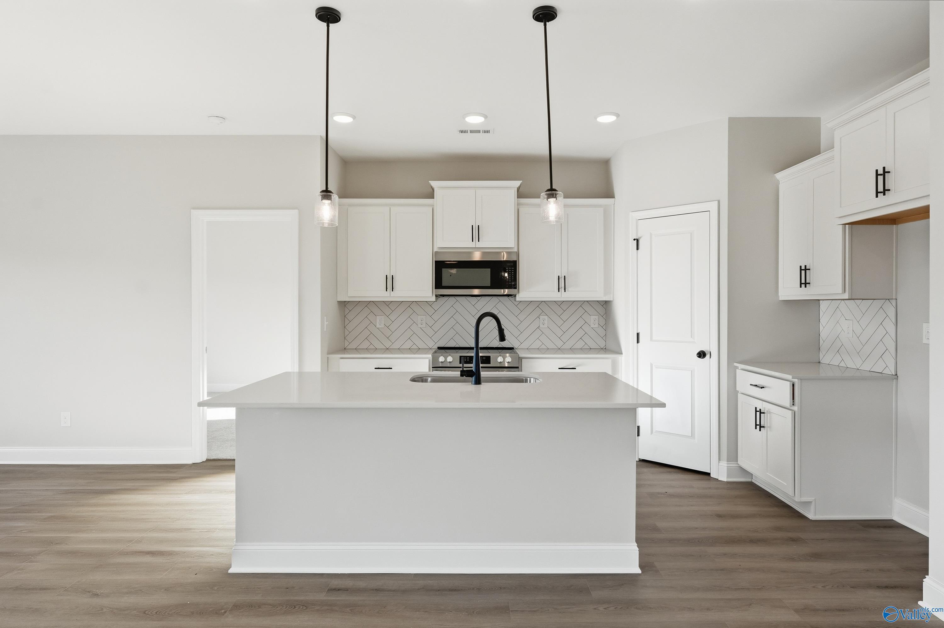Modern white kitchen island with stainless steel appliances and subway tile backsplash in Davidson Homes The Franklin E, Hazel Green, AL