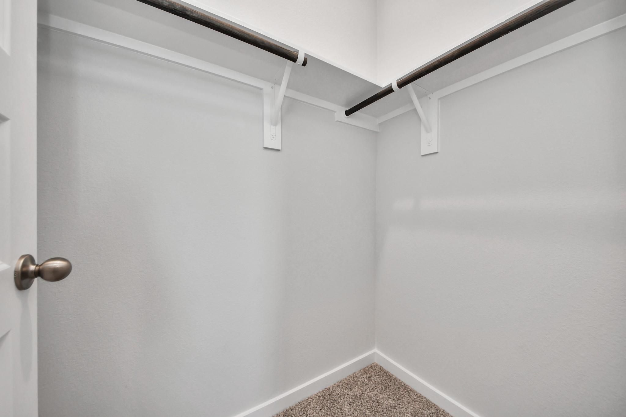 Walk-in closet with shelving and hanging rods in The Colorado G floor plan at Emberly in Beasley, Texas.