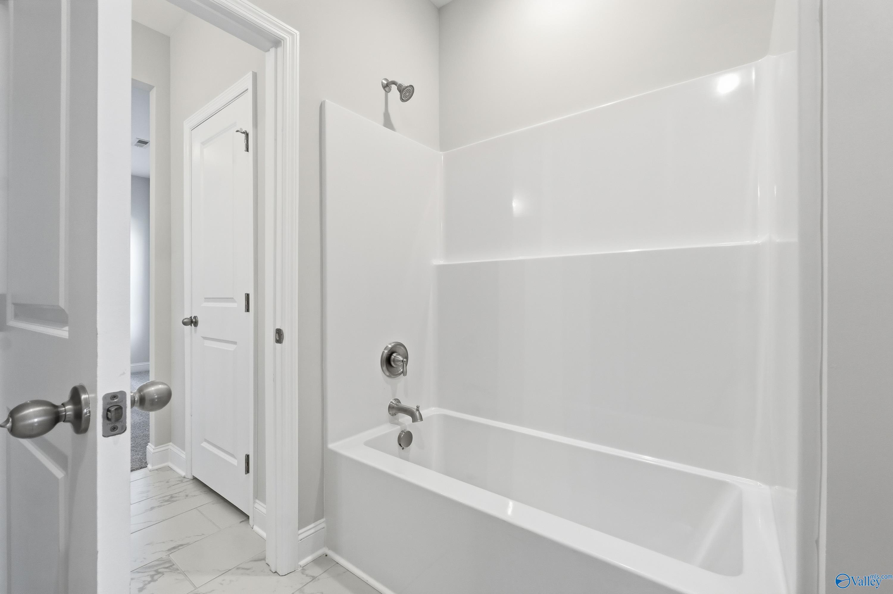 Spacious white bathroom with bathtub and glass shower enclosure in Davidson Homes The Finleigh, Creekside, Harvest, Alabama