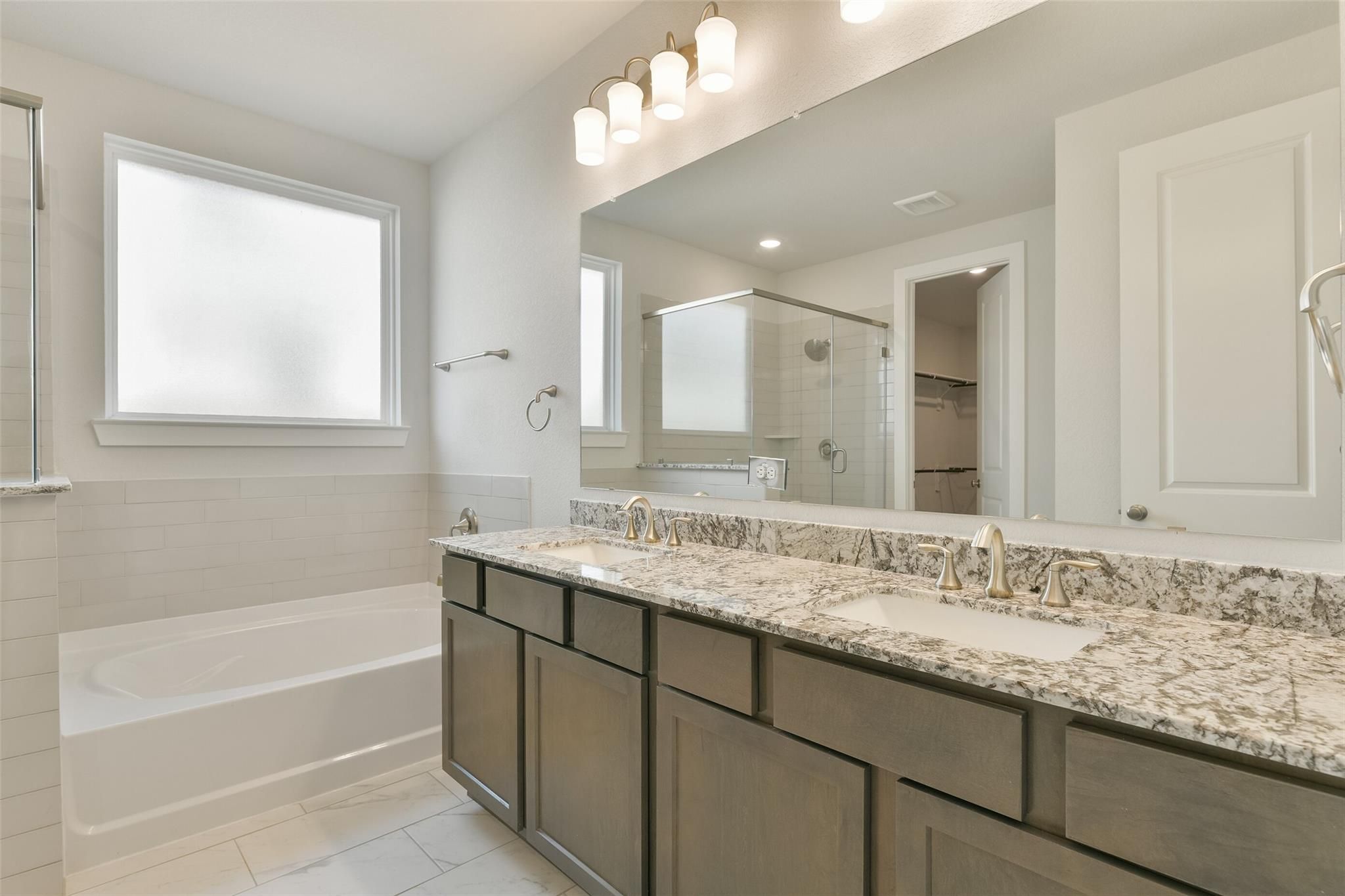 Modern master bathroom with double vanity, quartz countertops, freestanding tub, and glass shower in Davidson Homes Edward A, Texas City