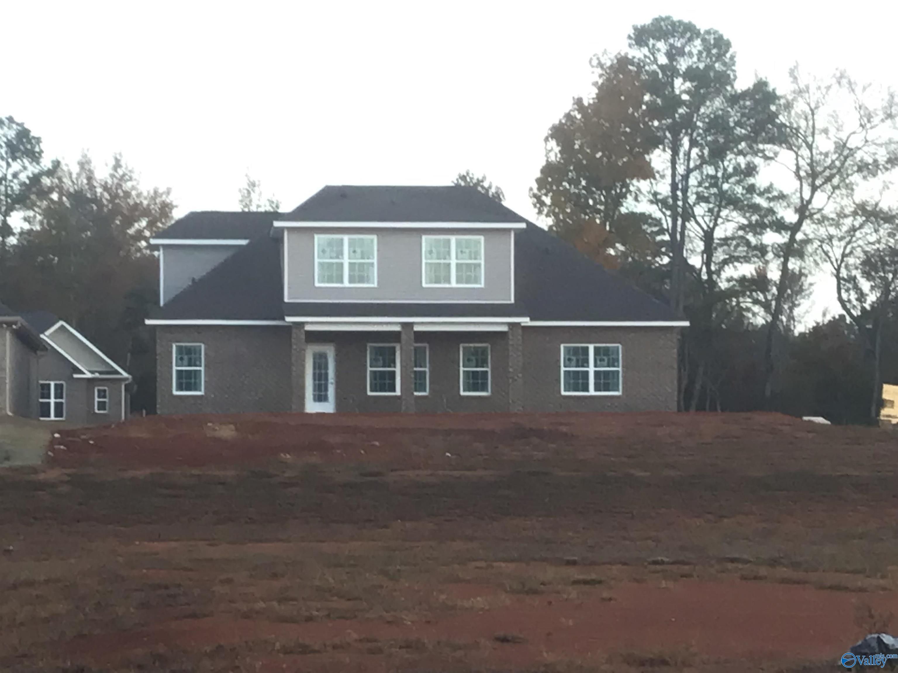 Modern gray brick ranch home with large windows, black roof, and wooded lot in River Road Estates, Decatur, Alabama