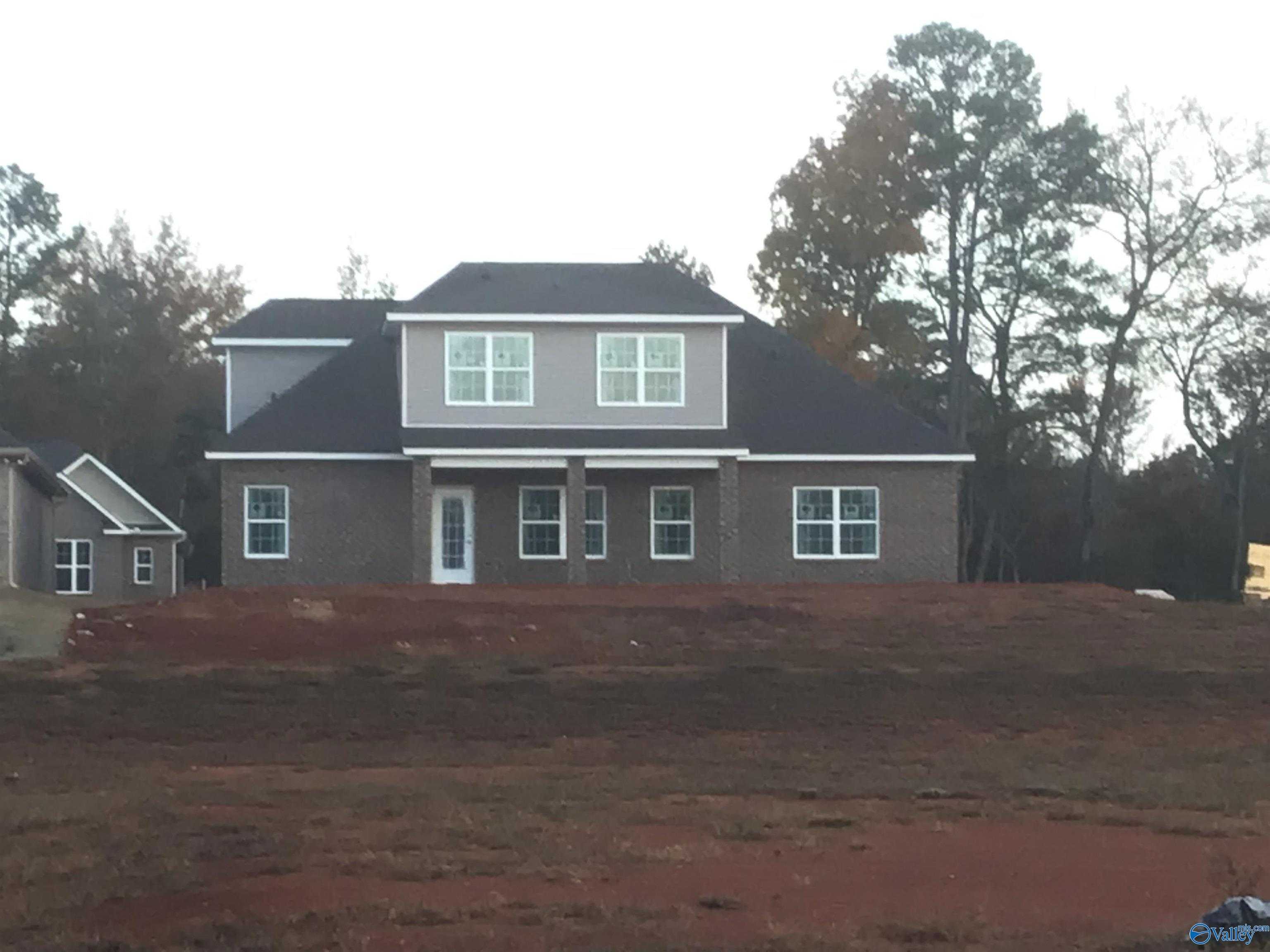 Modern gray brick ranch home with large windows, black roof, and wooded lot in River Road Estates, Decatur, Alabama