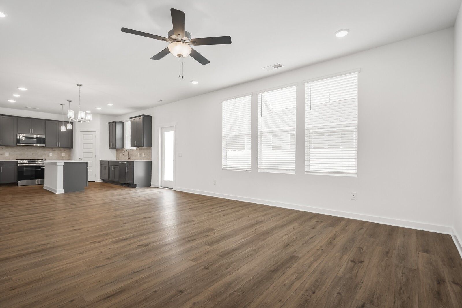 Open-concept kitchen with dark cabinets, island, hardwood floors, and large windows in Davidson Homes The Gordon C, White House, TN
