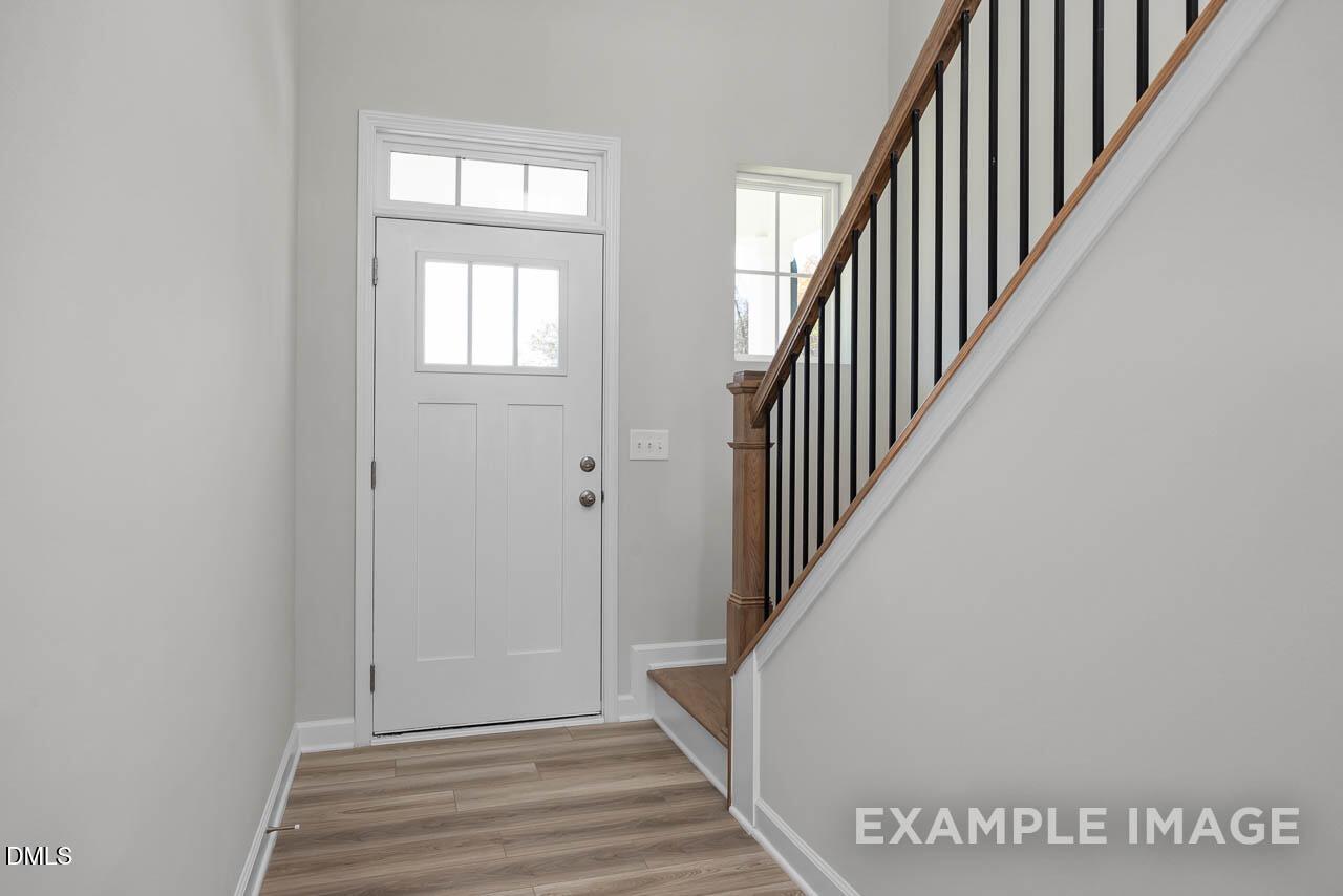 Bright entry foyer with white sidelight door and oak staircase in Davidson Homes The Adalynn A, Lillington, NC