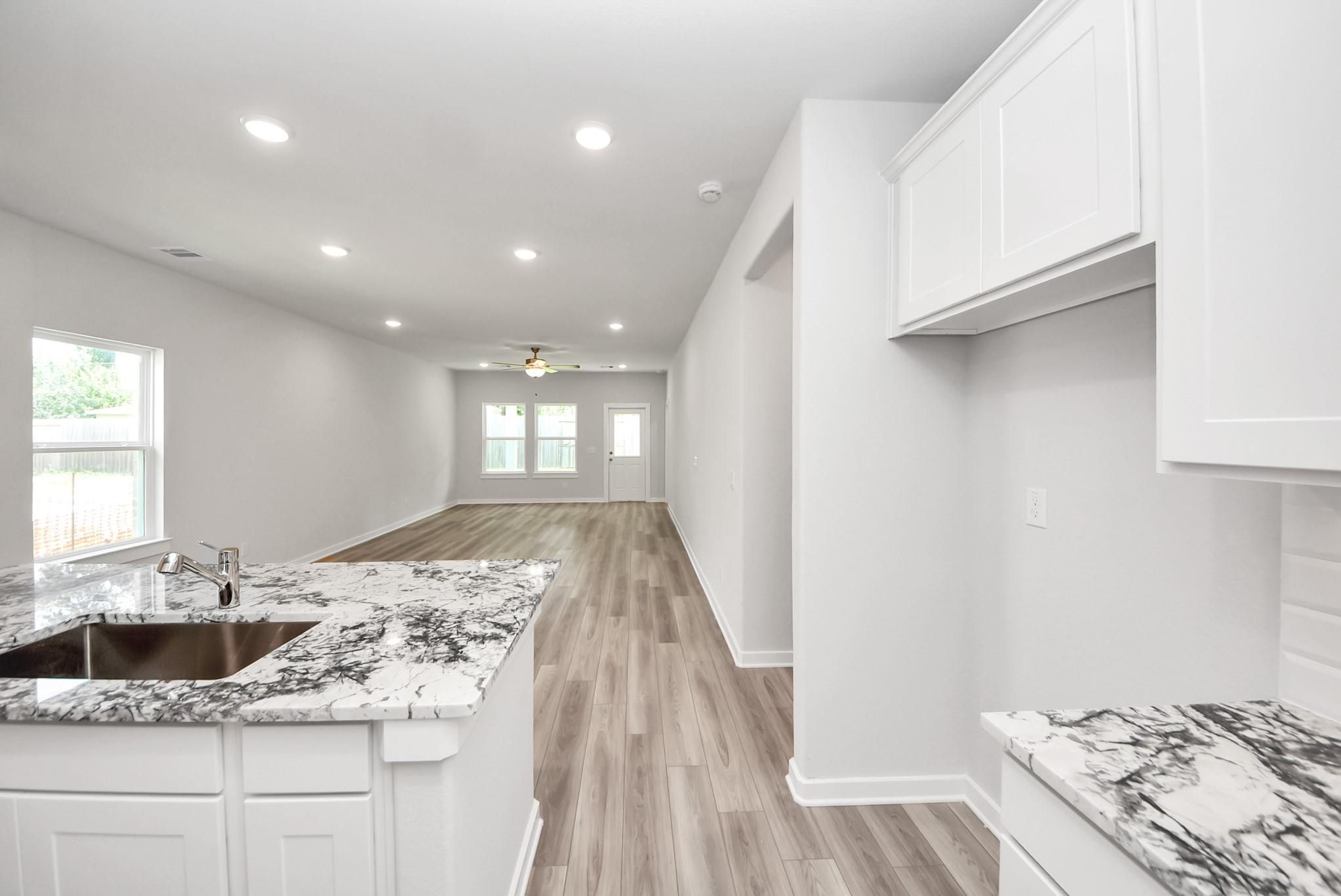 Open-concept kitchen with marble countertops overlooking the living area in The Sabine E floor plan at Windmill Estates.