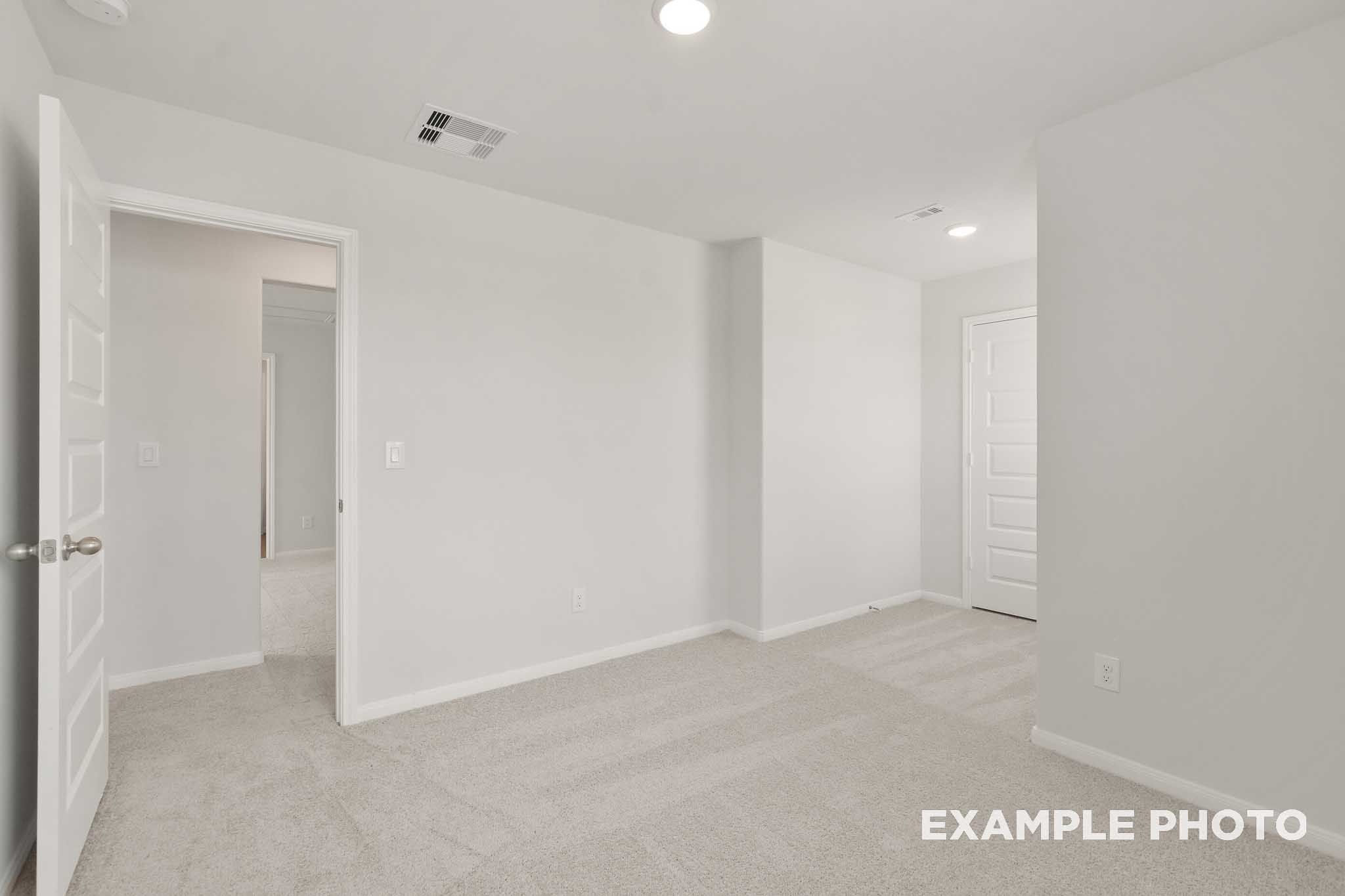 Spacious carpeted bedroom with white doors in The Brazos, a Davidson Homes 5-bedroom new construction in Beasley, Texas
