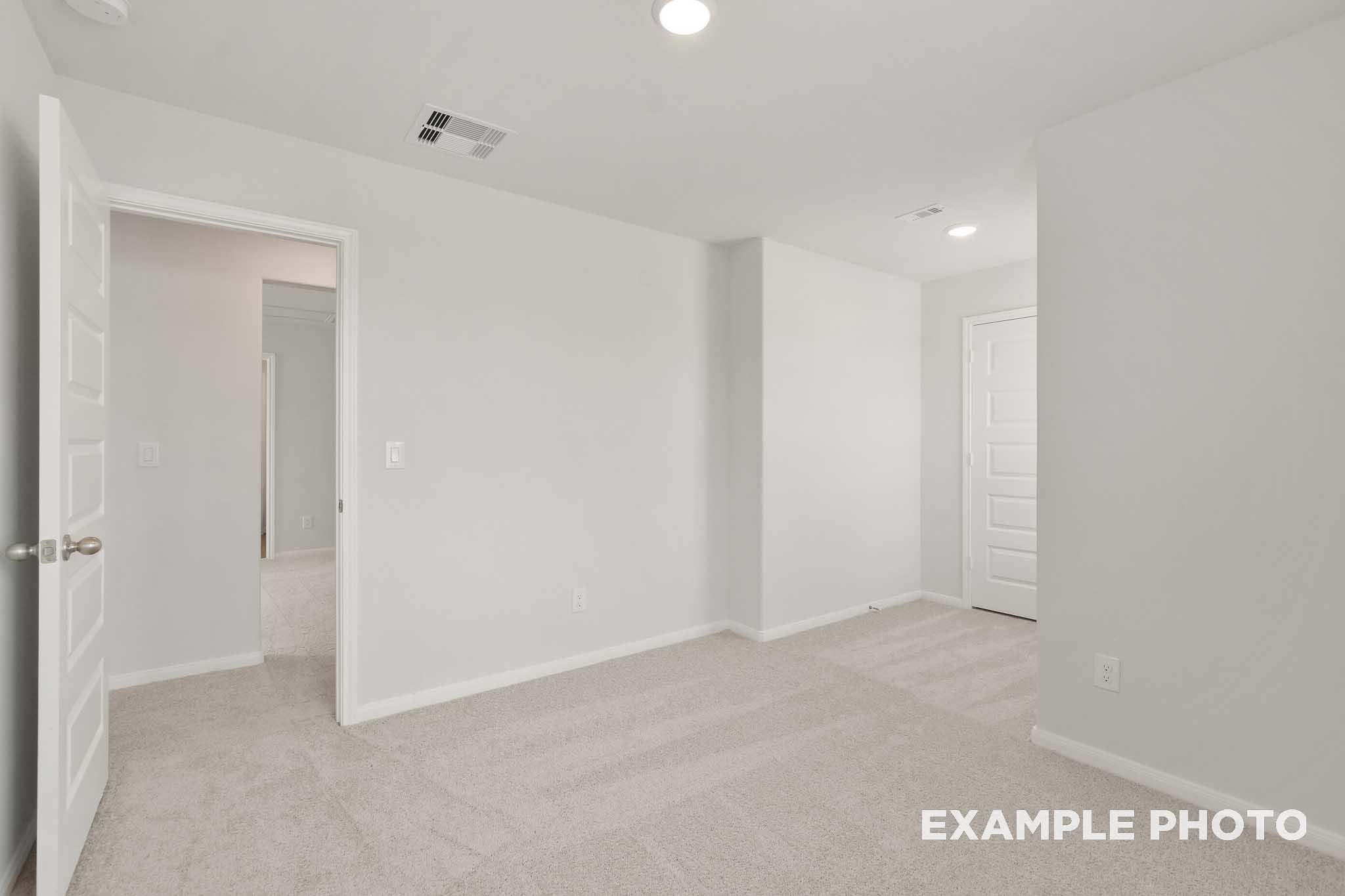 Spacious carpeted bedroom with white doors in The Brazos, a Davidson Homes 5-bedroom new construction in Beasley, Texas