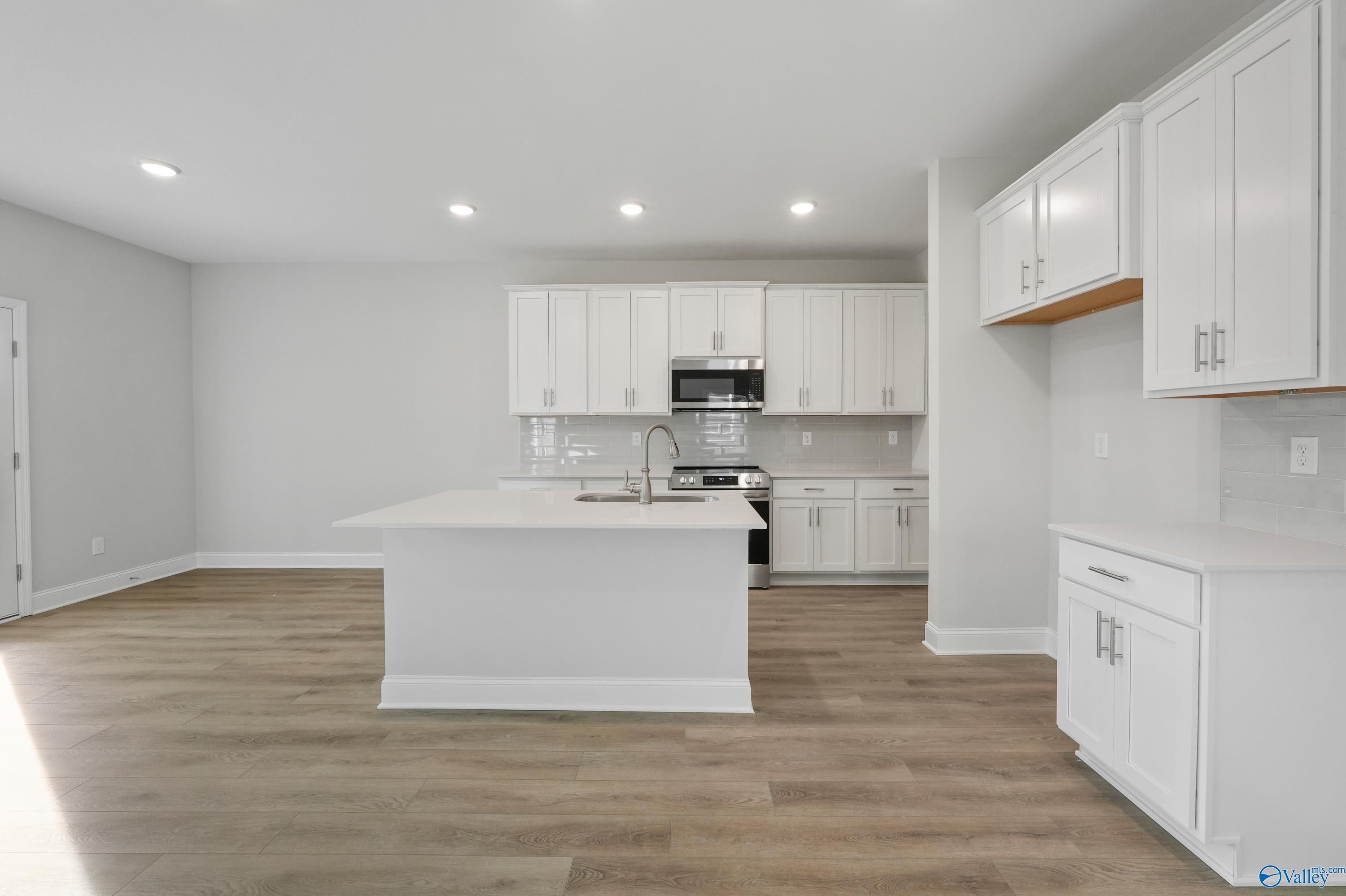Spacious modern kitchen with white cabinets, stainless appliances, and large island in Davidson Homes The Camden, Huntsville AL