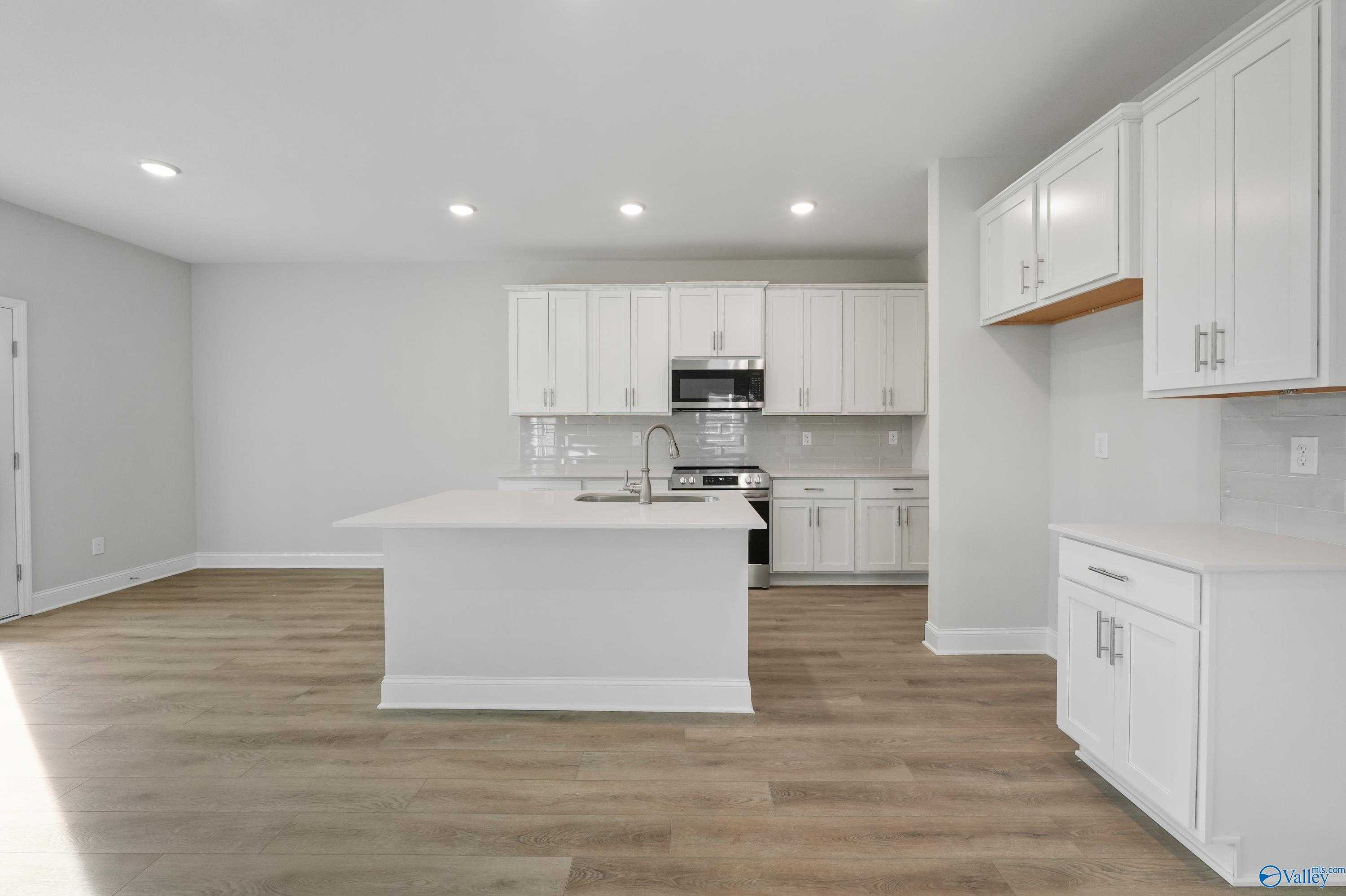 Spacious modern kitchen with white cabinets, stainless appliances, and large island in Davidson Homes The Camden, Huntsville AL