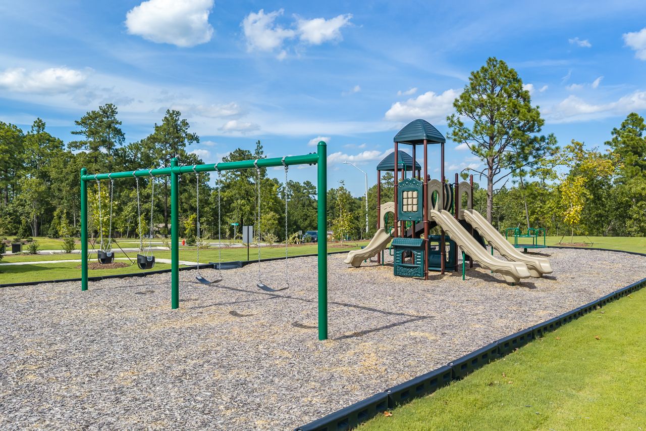 Community playground at Montrose in Aberdeen, NC by Davidson Homes featuring swings, slides, and mulch play area