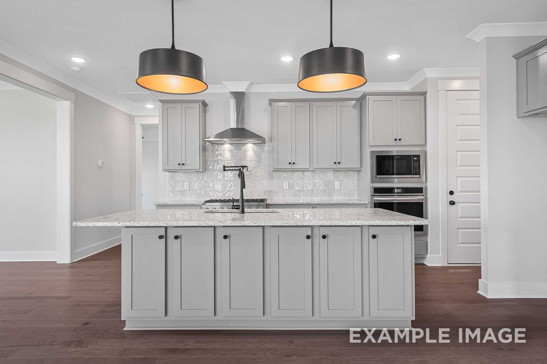 Modern kitchen in The Hathaway home with light gray shaker cabinets, large center island, subway tile backsplash, and pendant lighting