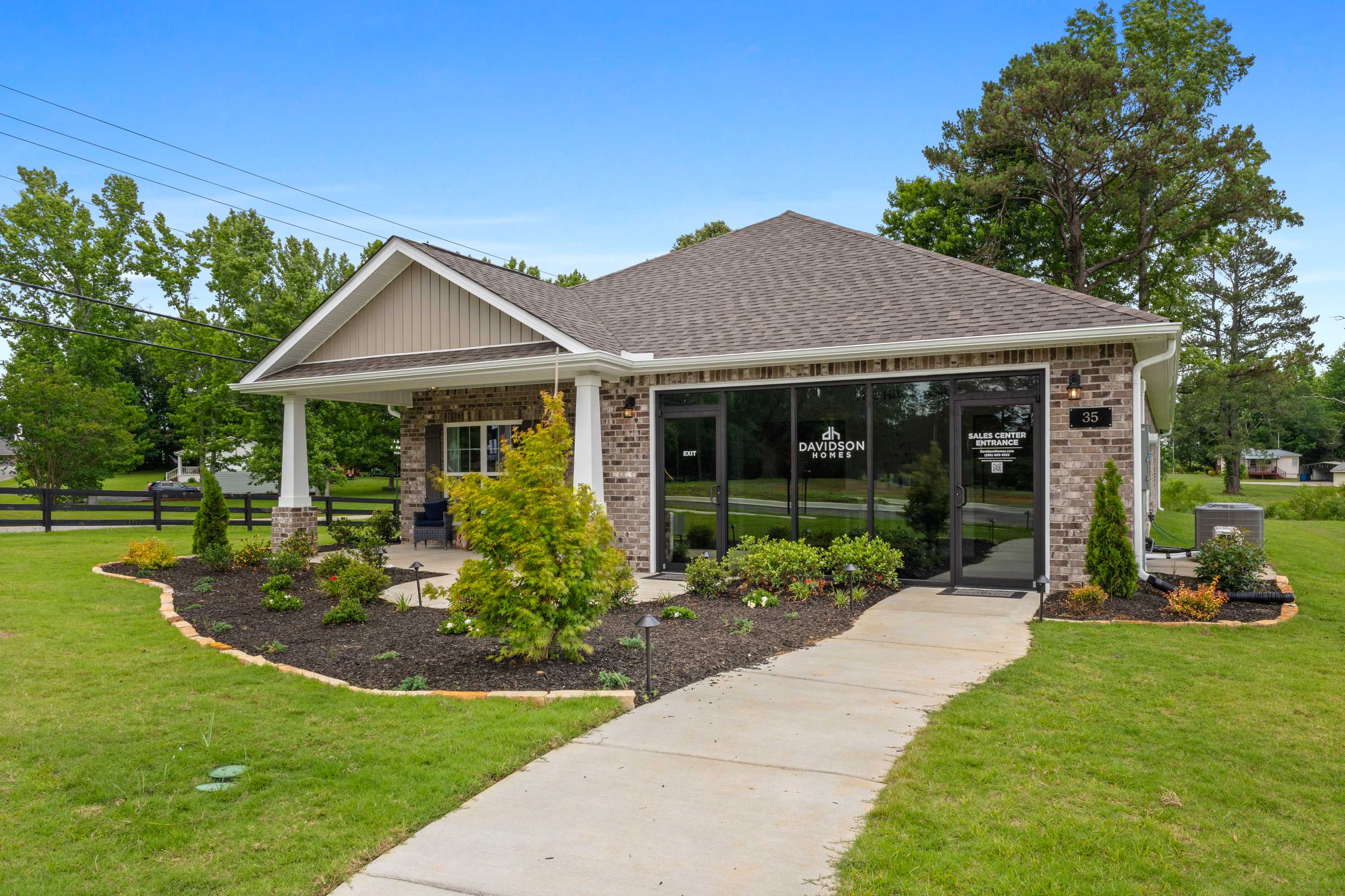 Davidson Homes sales office at The Highlands in Arab Alabama with covered porch, brick exterior, and lush landscaping