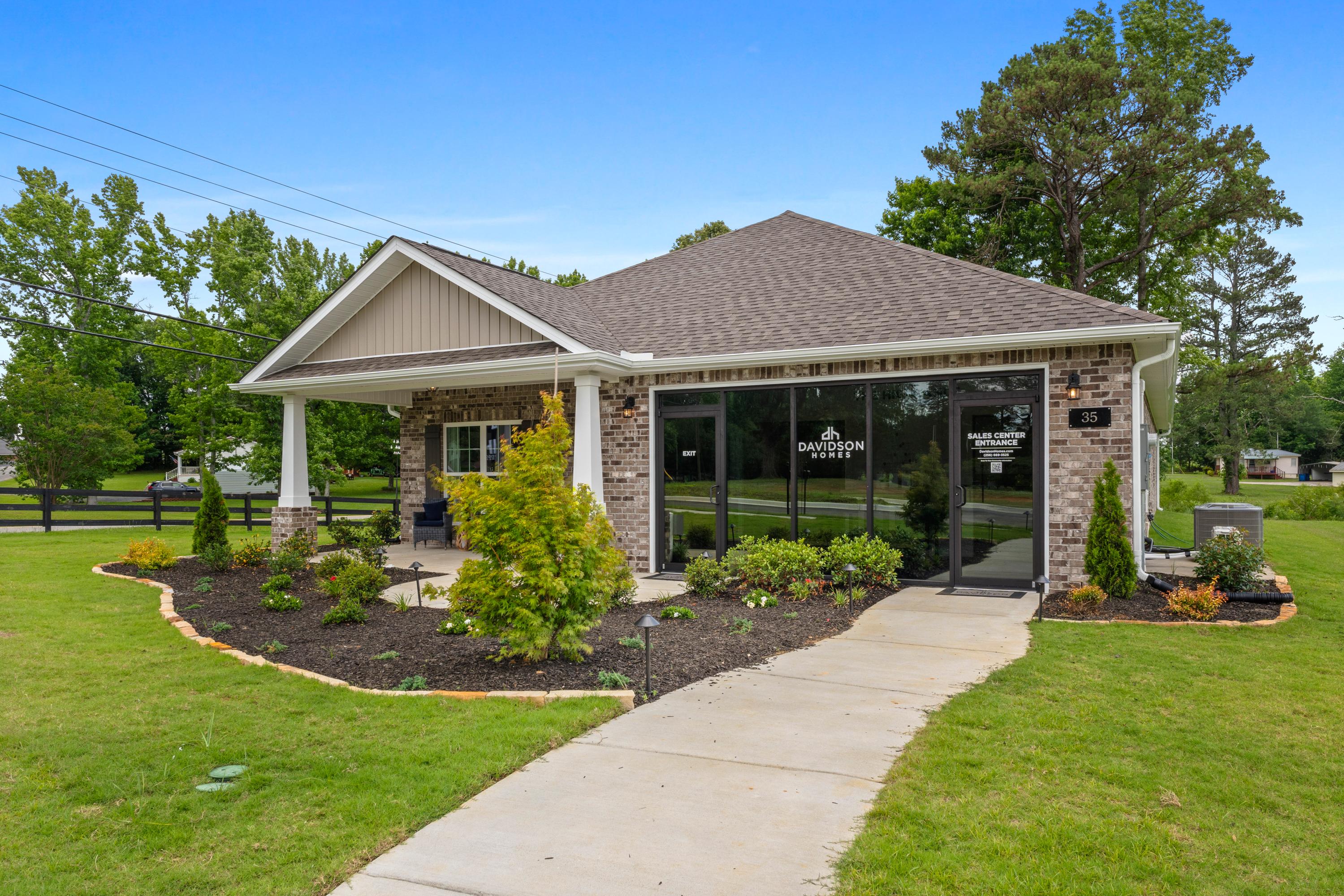 Davidson Homes sales office at The Highlands in Arab Alabama with covered porch, brick exterior, and lush landscaping