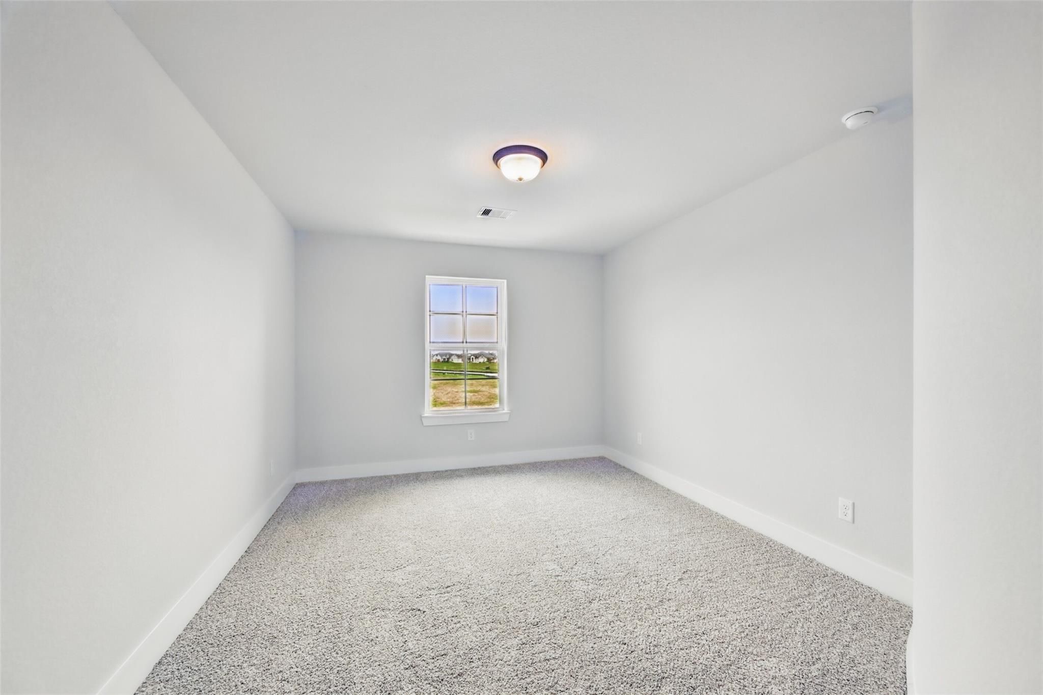 Bright empty bedroom with large window, gray walls, carpet in Davidson Homes The Victoria C, Lago Mar, Texas City