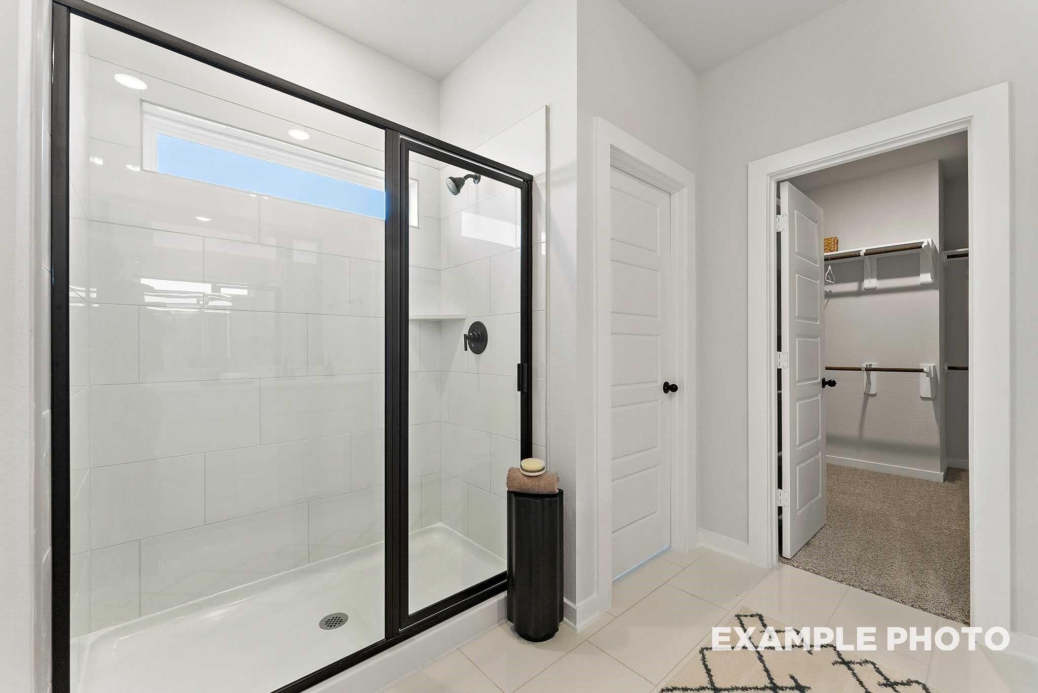 Modern walk-in shower with black trim and spacious walk-in closet in The Everett E floor plan, Sundance Cove, Crosby, TX.